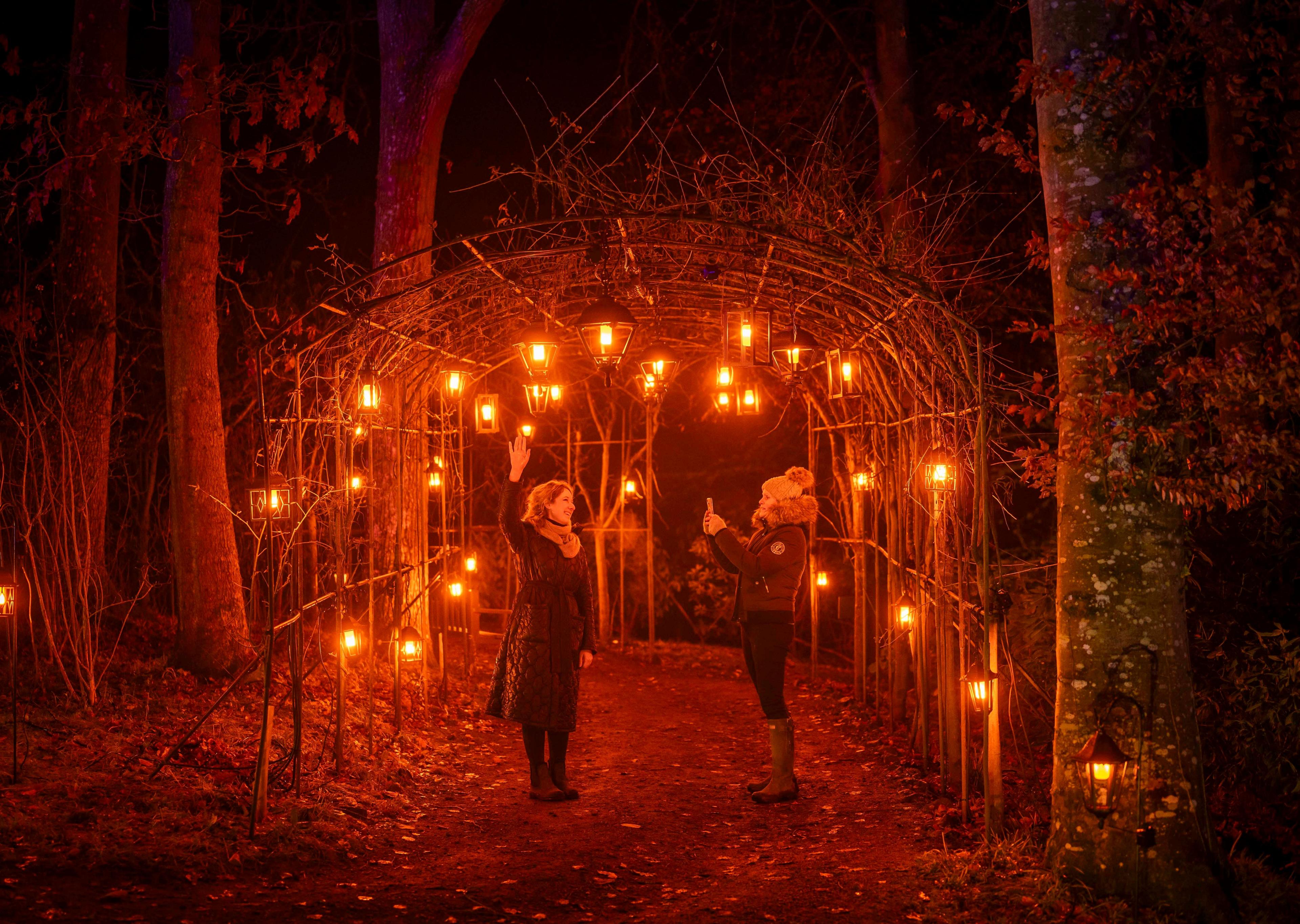 Two people take a picture underneath a tunnel of hanging lights