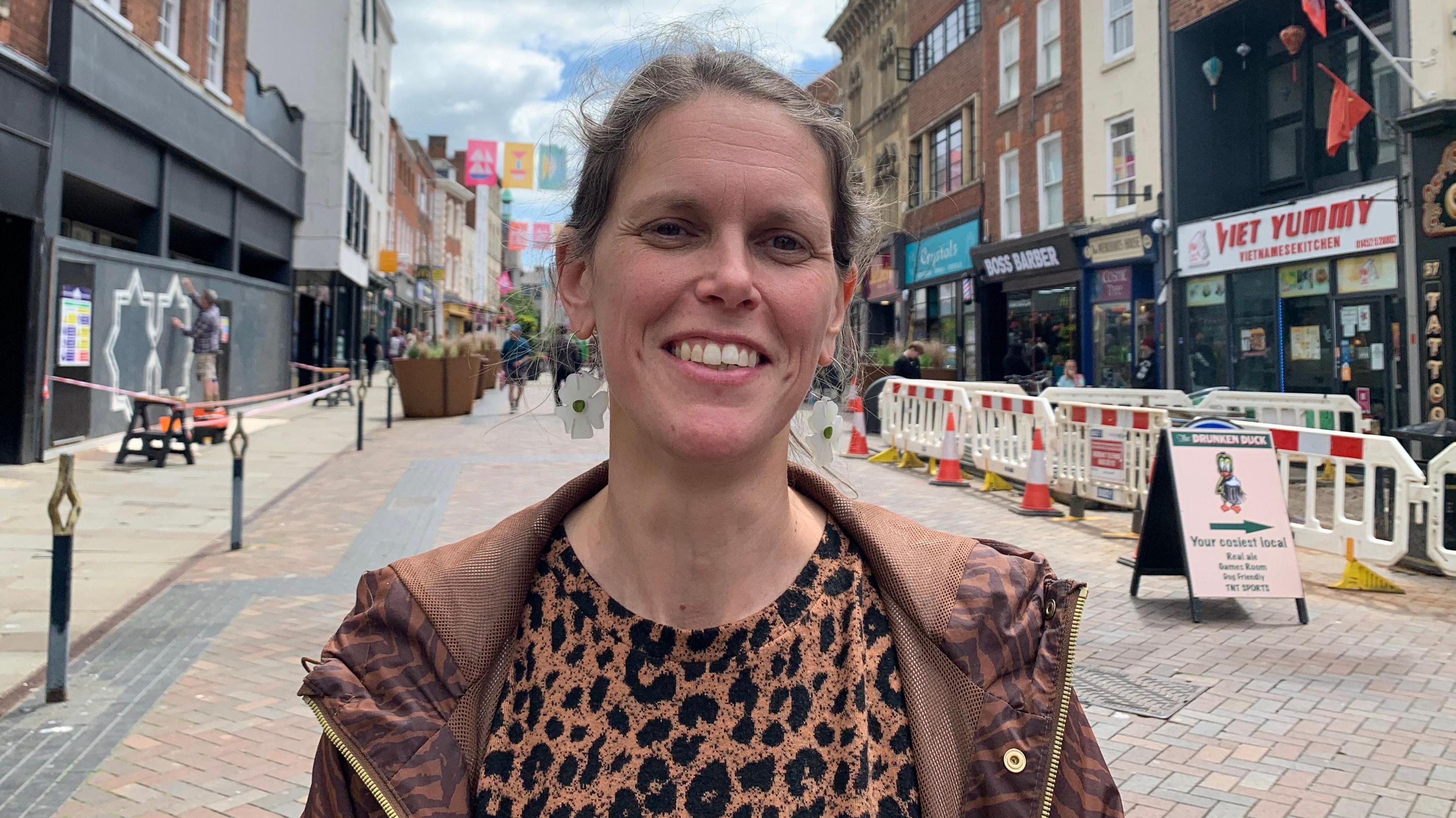 A photo showing Emily Gibbon from Gloucester BID standing in a street in Gloucester with shop fronts either side