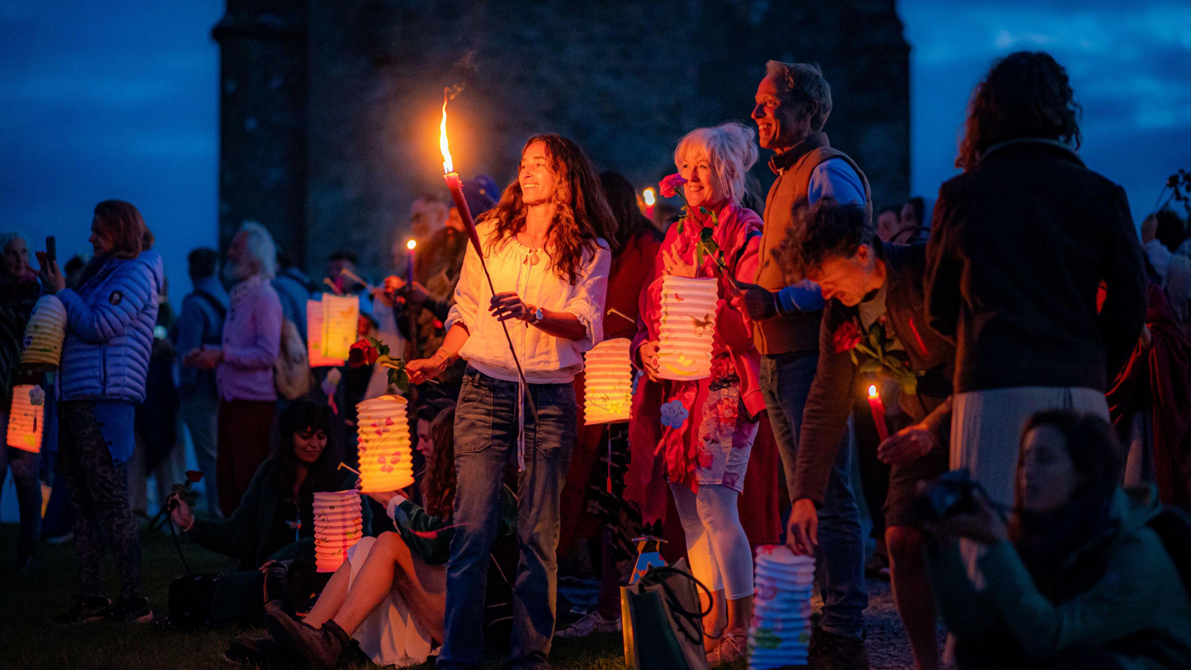 People carrying lanterns and candles