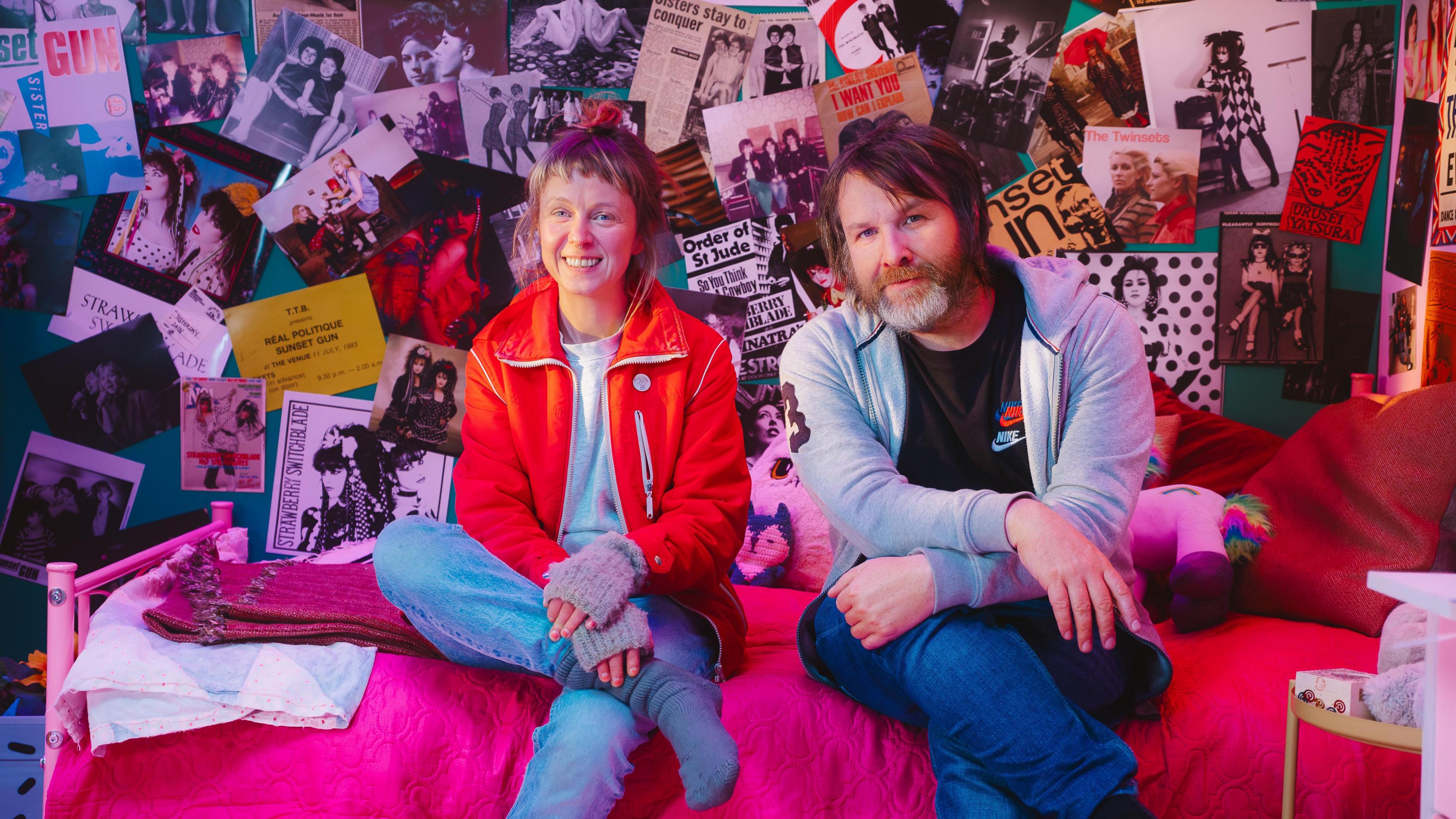 Since Yesterday's co-directors Carla J Easton and Blair Young, sitting on a bed surrounded by pictures and posters of girl bands.