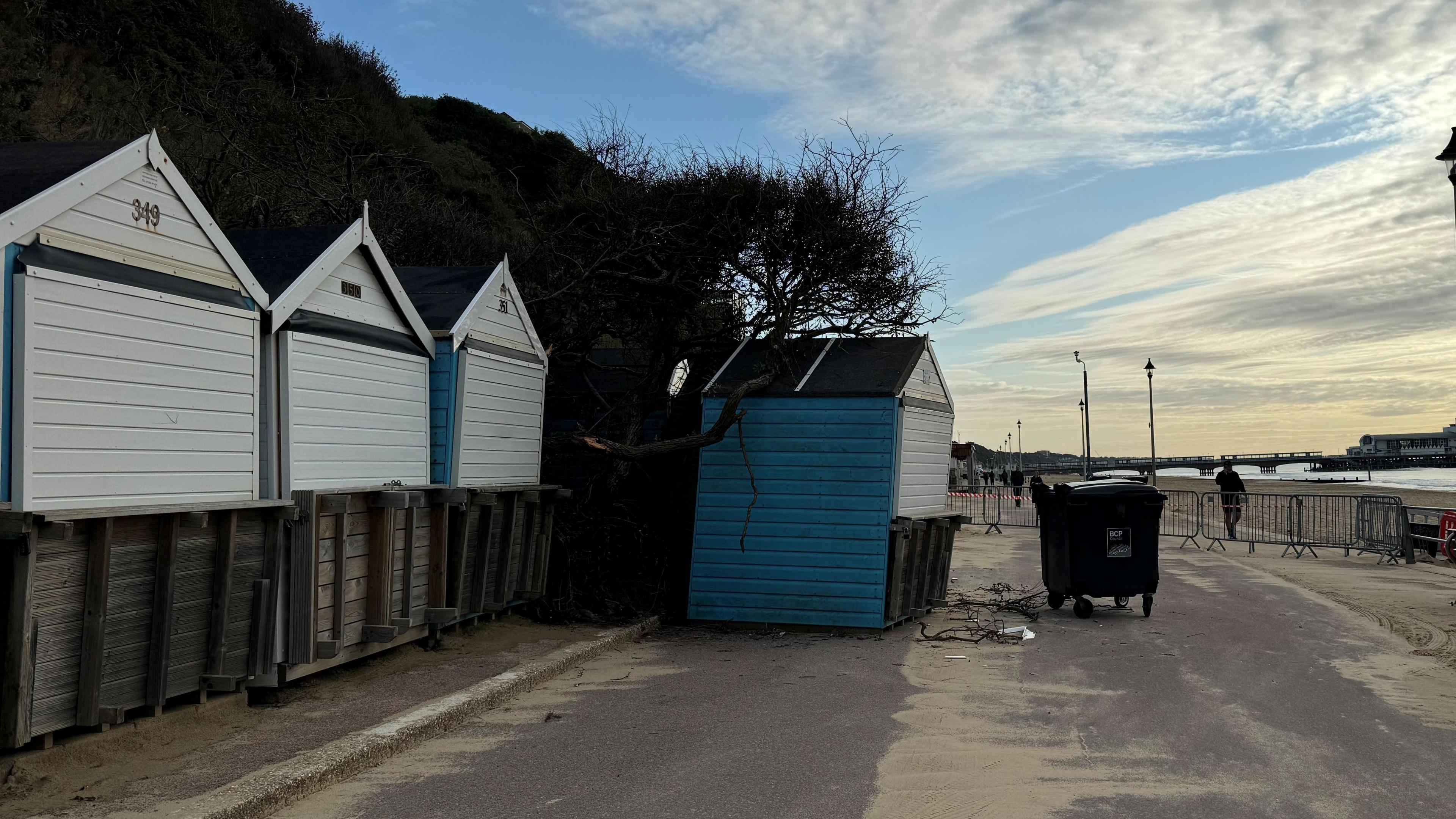 Beach huts at Durley Chine, which are wooden with pointed roofs. Behind them is a cliff