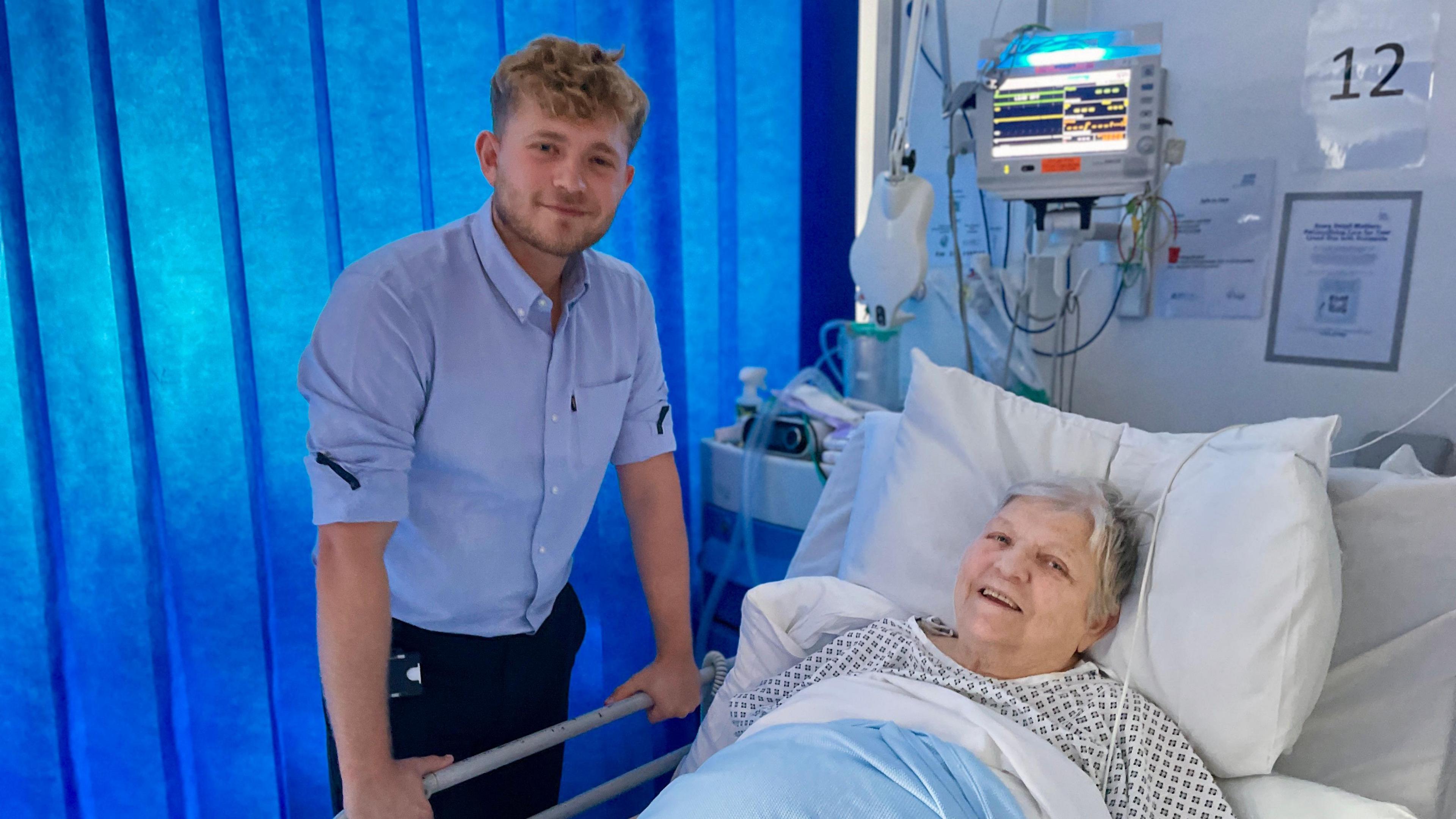 Dr Alfie Wain standing at a female patients bedside. 