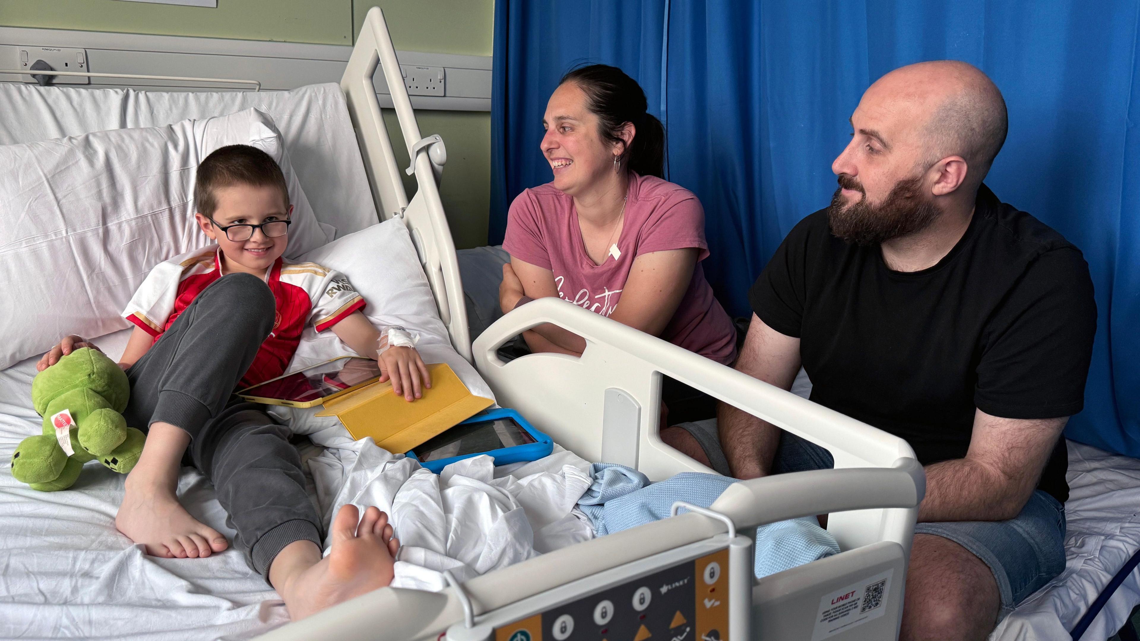 Reece lying in a hospital bed, next to his mother Elizabeth and his father Ashley