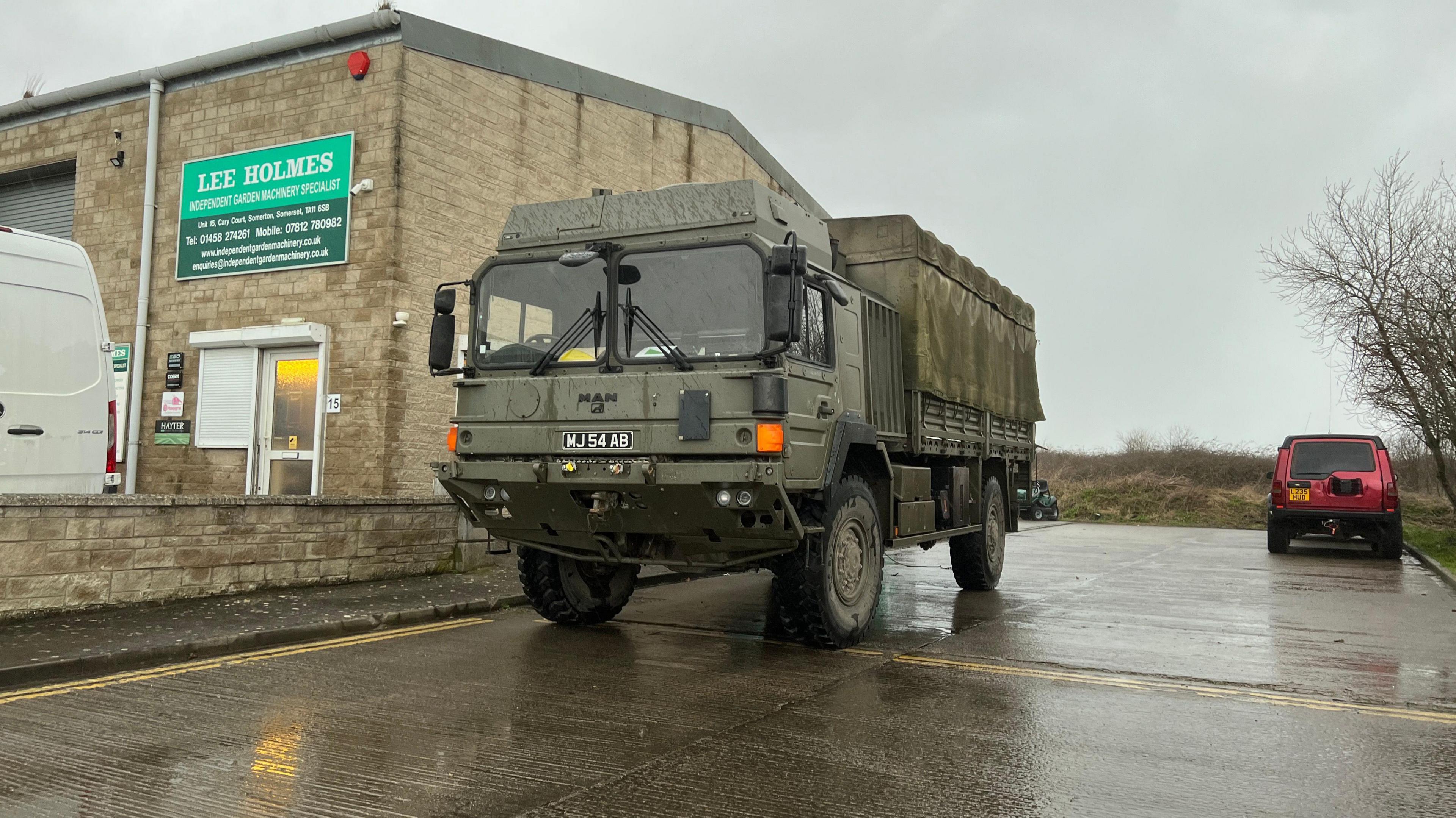 An army truck arrives at a rest centre in Somerset. It is a large dark green vehicle