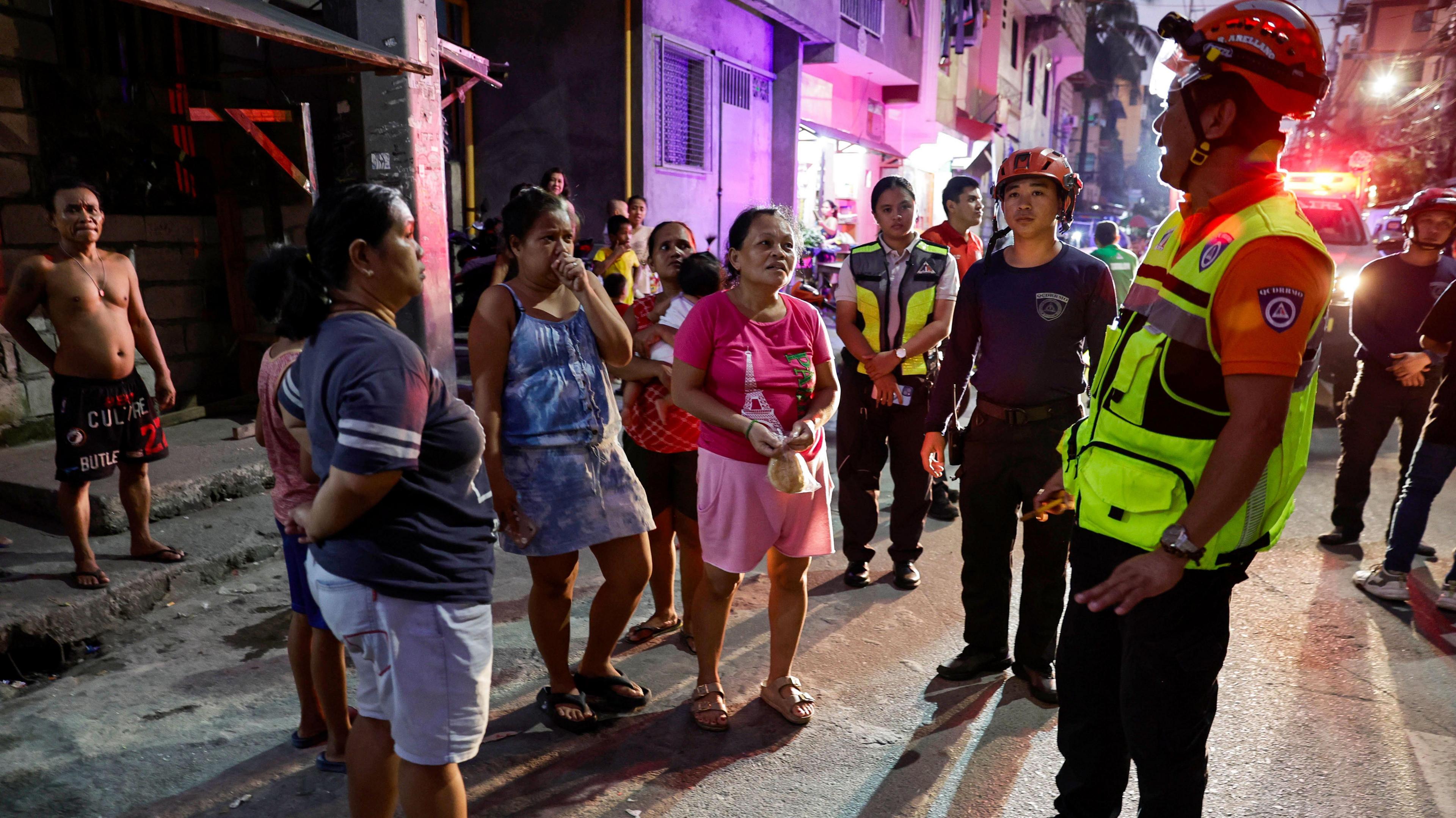 A man wearing a high-viz vest and helmet speaks to a group of people