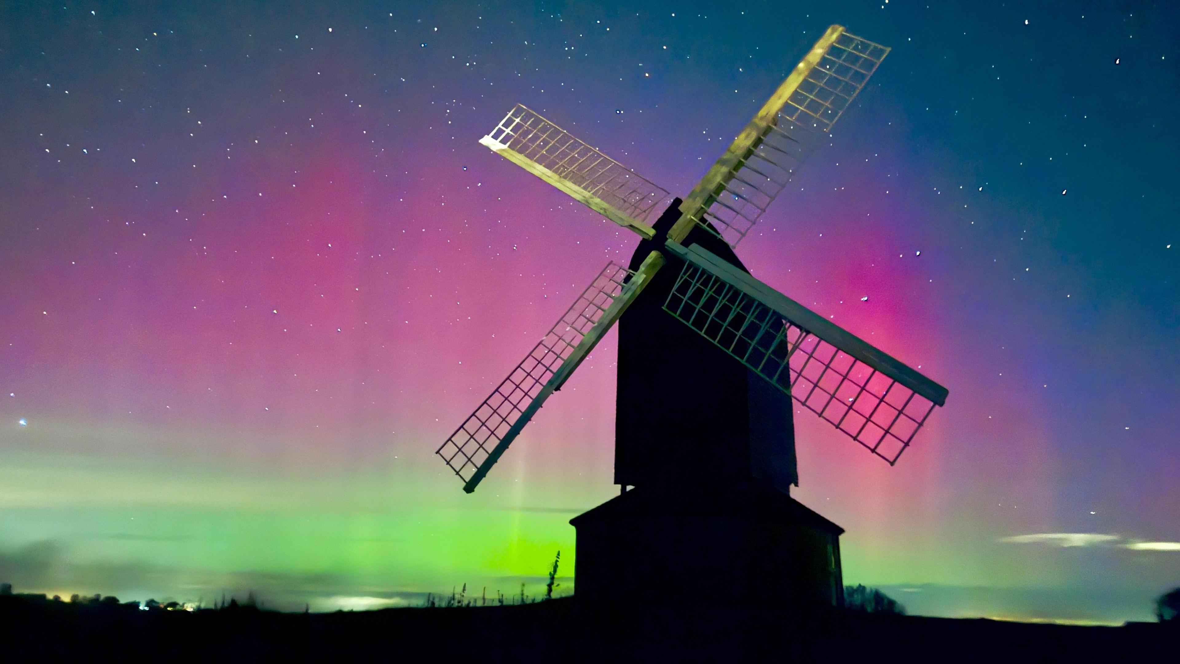 Old windmill dominating the picture with the Northern Lights in the night sky behind