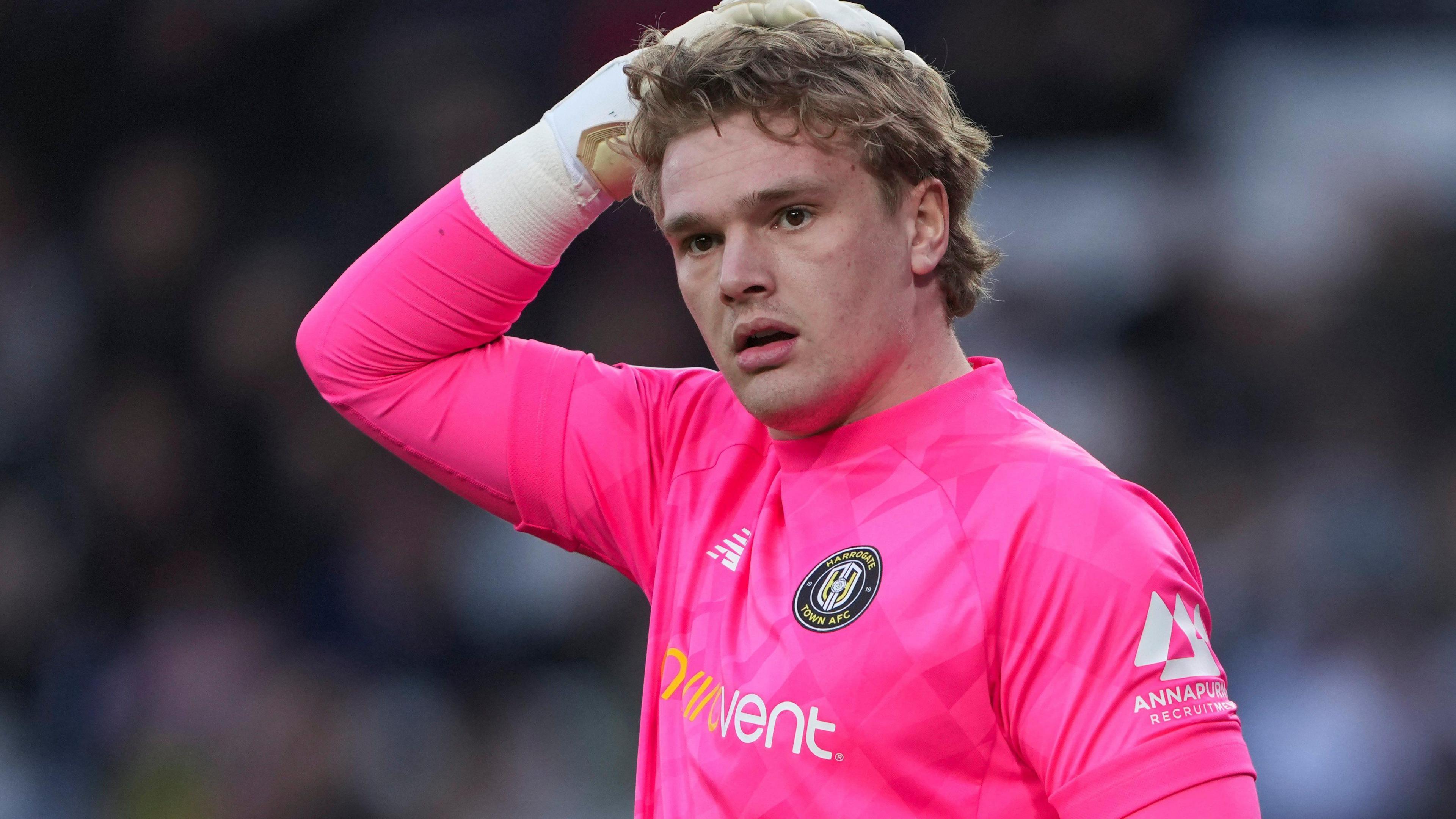 Sam Waller in action for Harrogate Town wearing a pink goalkeeper shirt