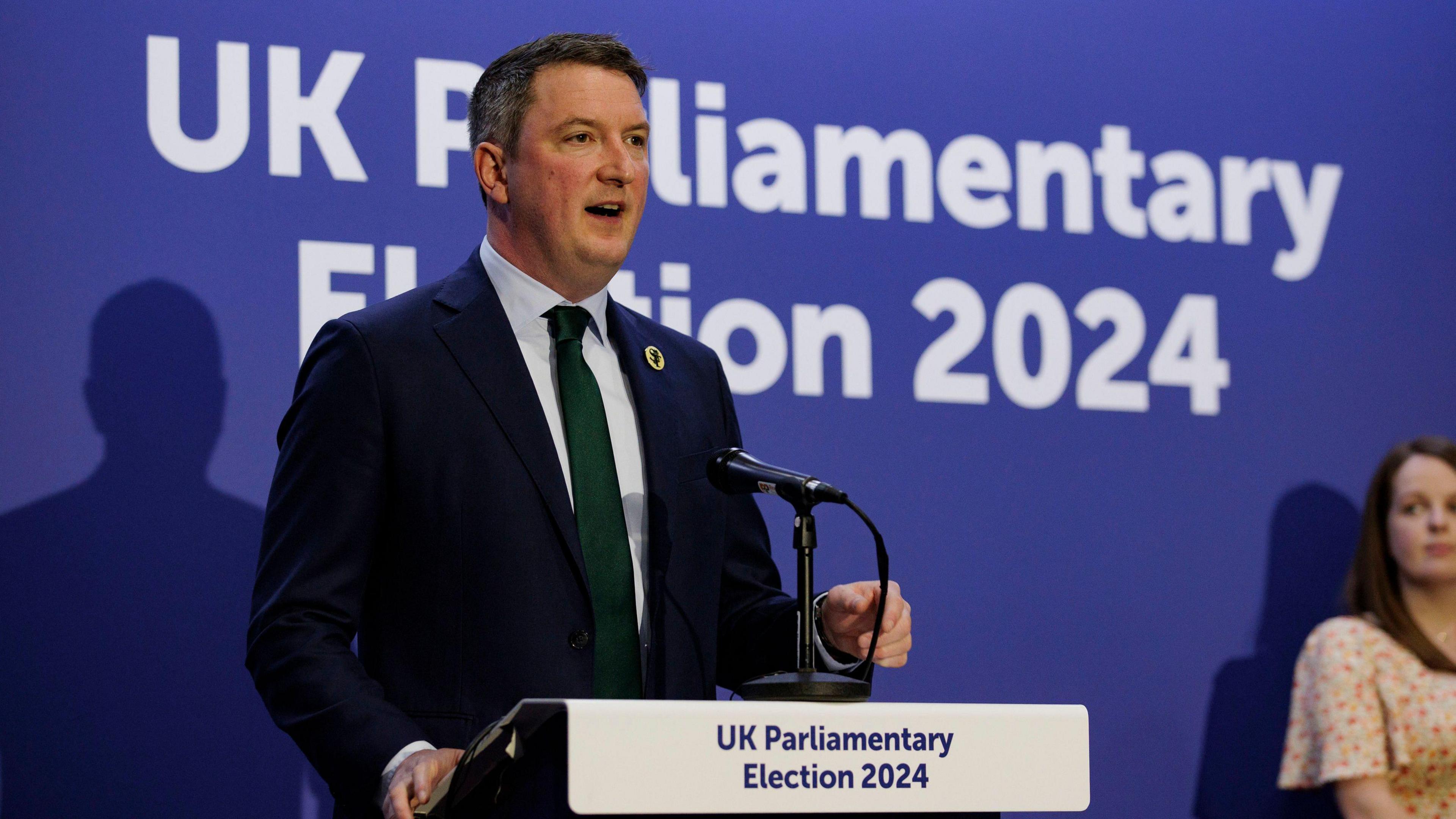 John Finucane standing behind a podium 