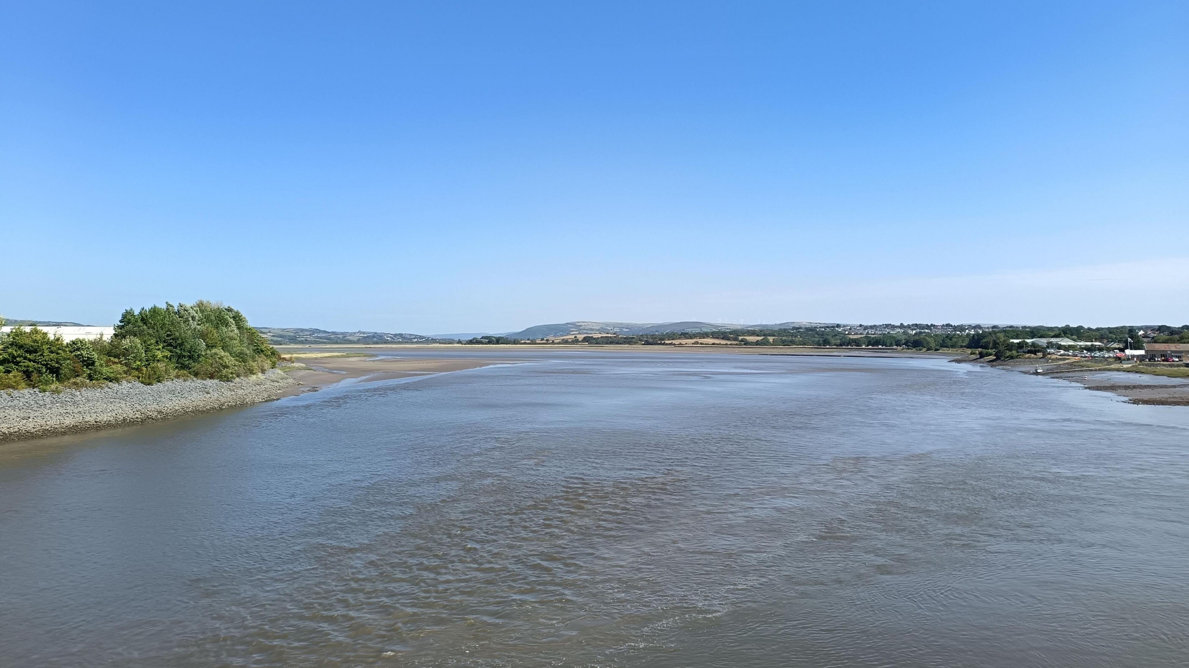 A large river surrounded by two banks, leading out to sea