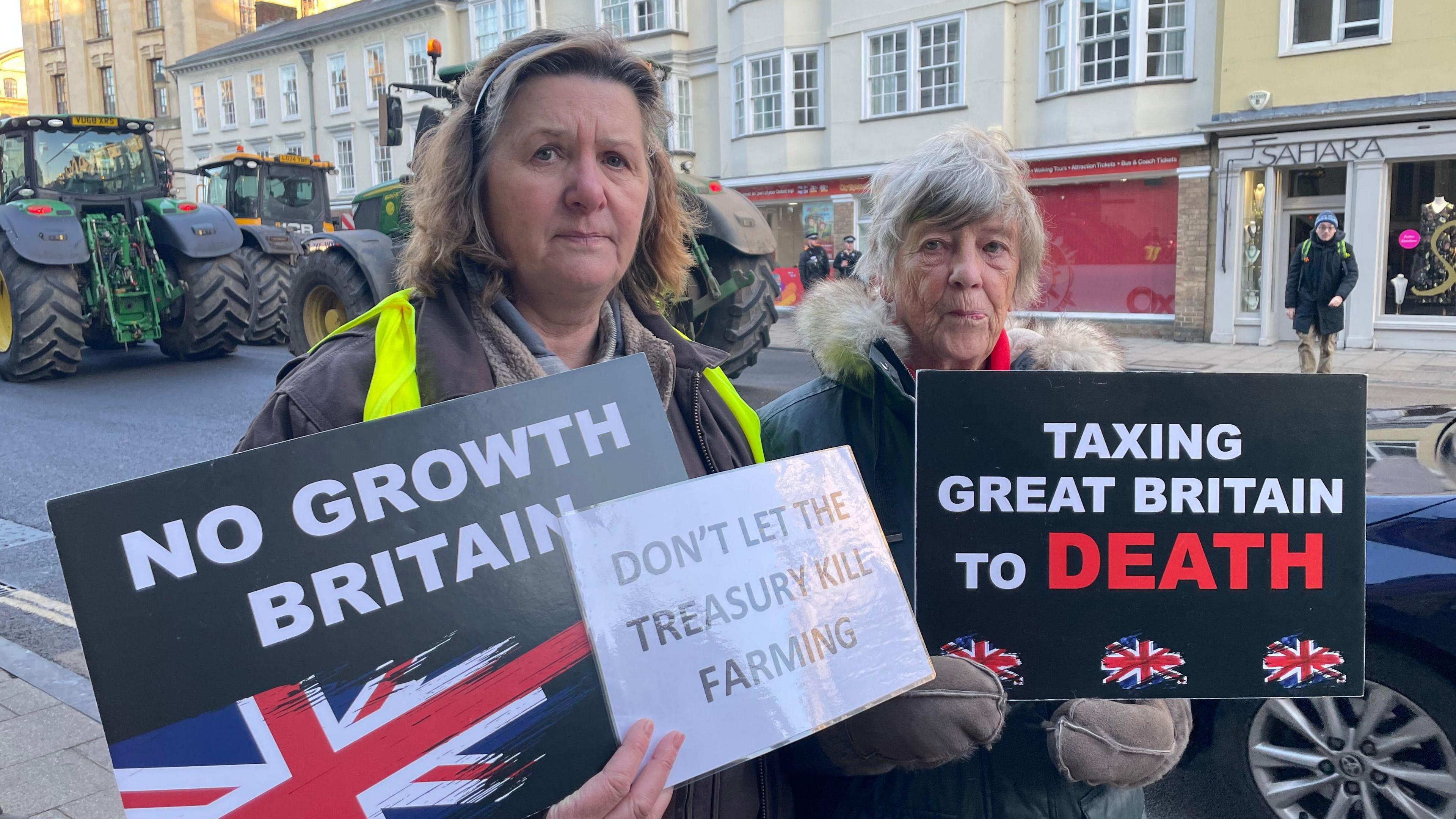 Caroline Graham and fellow protestor holding signs saying No Growth Britain, and Don't let the Treasury kill farming