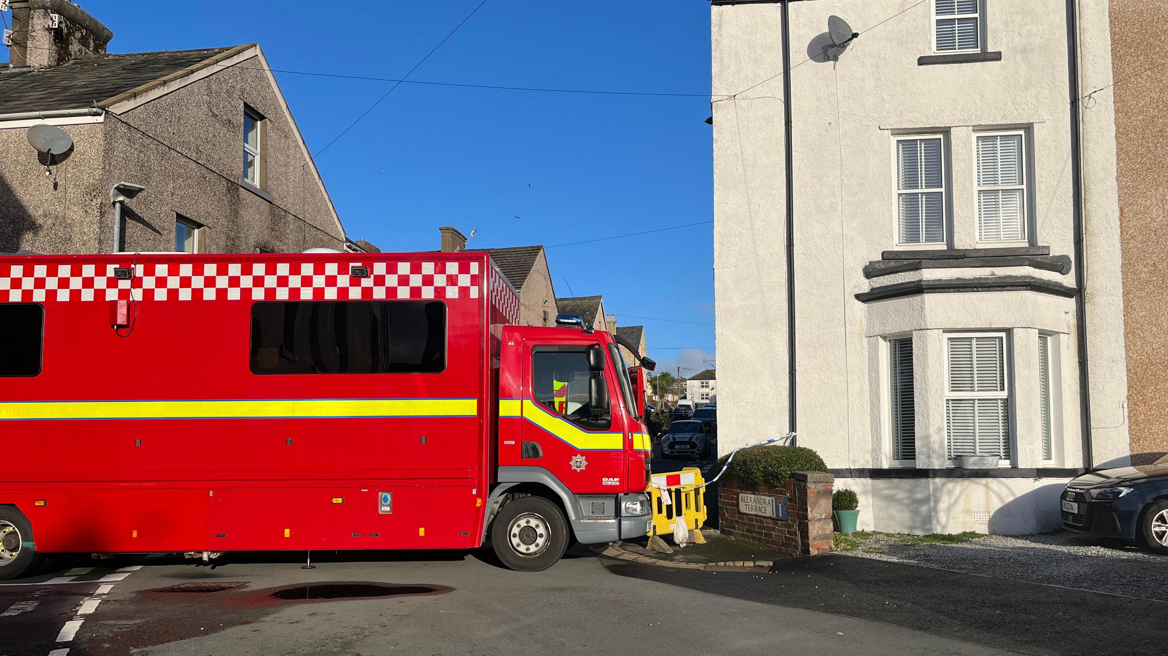 A red fire truck is parked in front of a street, blocking off the path.