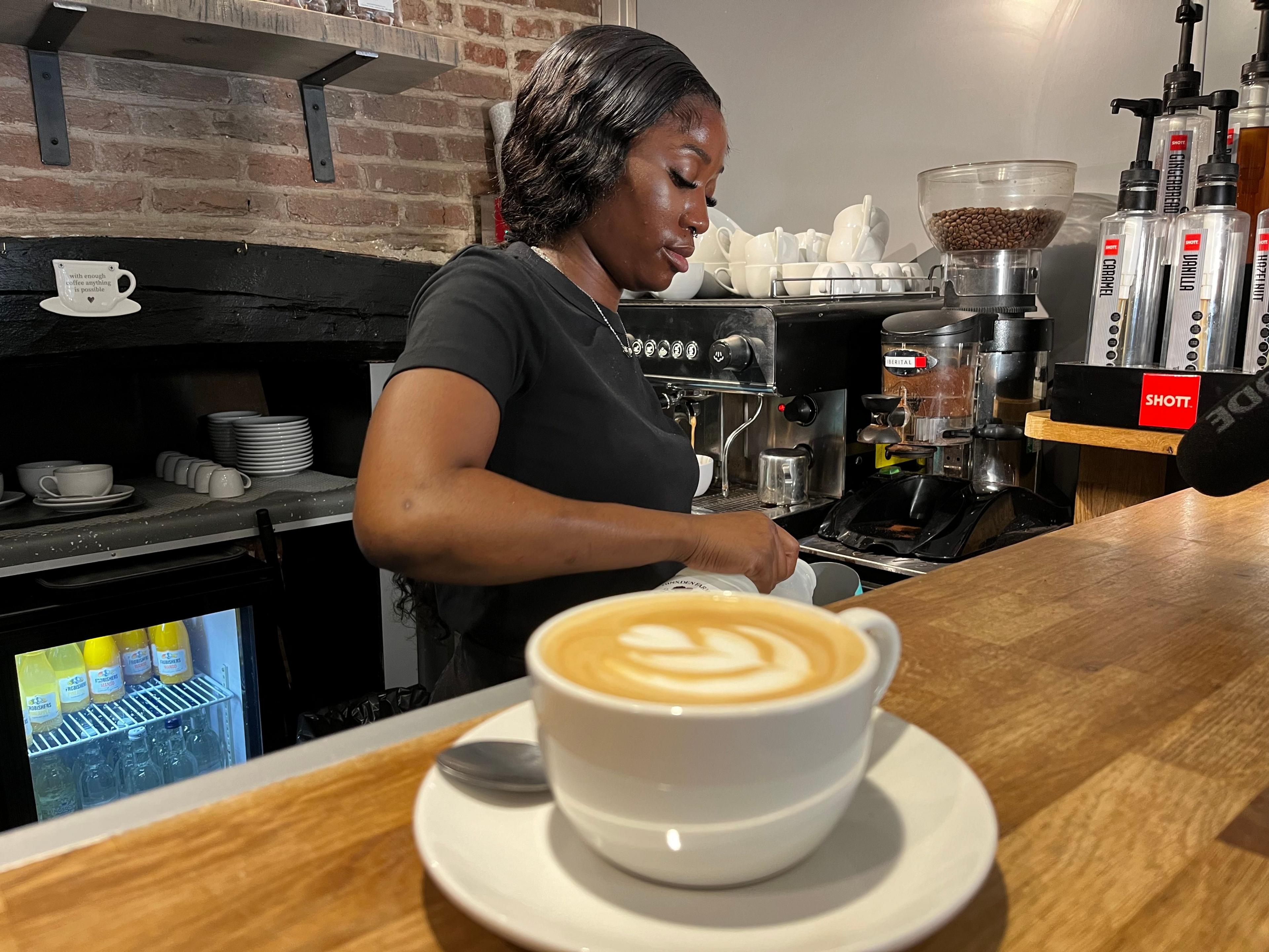 Barista prepares coffee using an espresso machine at a cafe in Canterbury