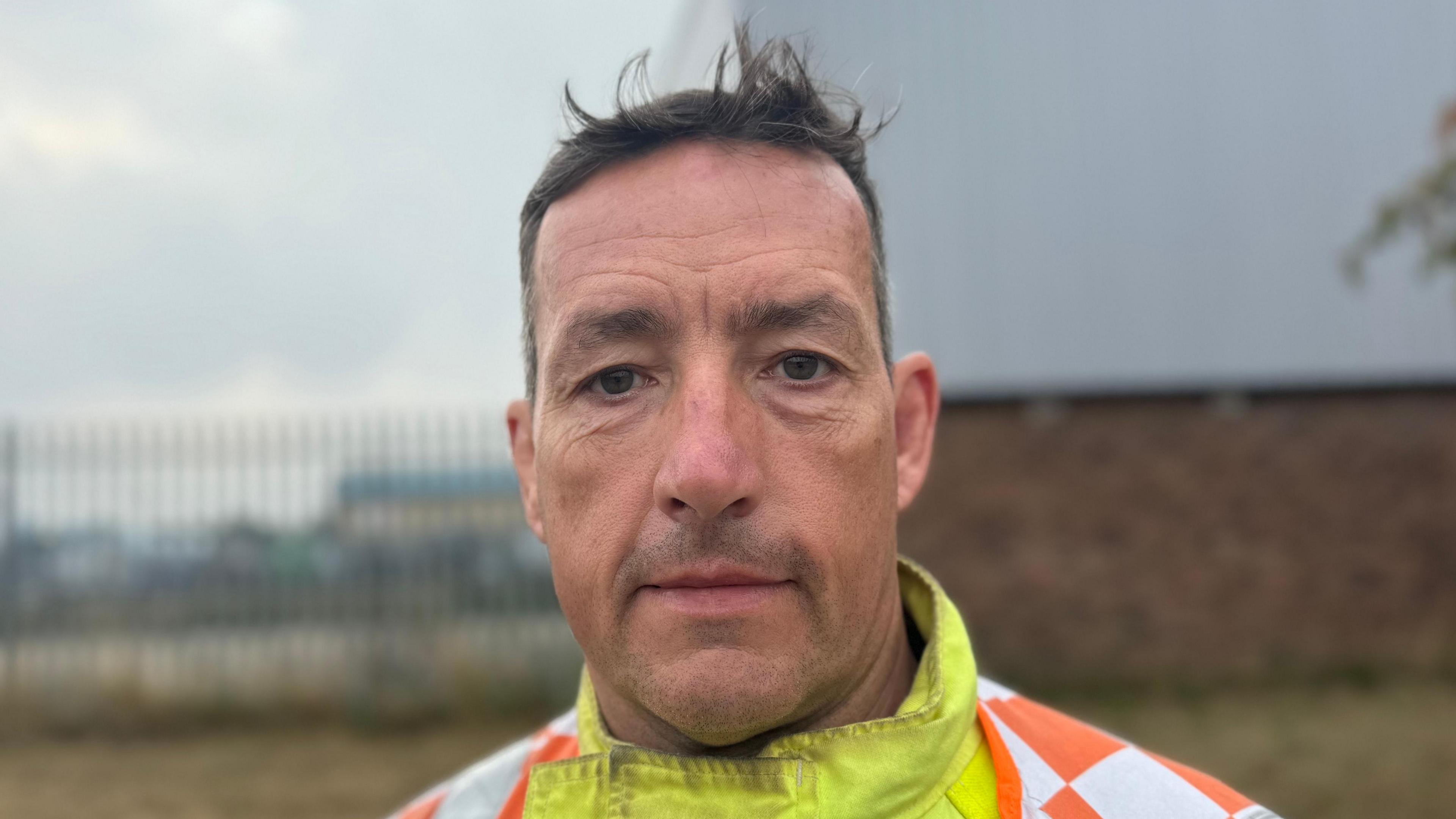 A man looking straight at the camera wearing fire gear.