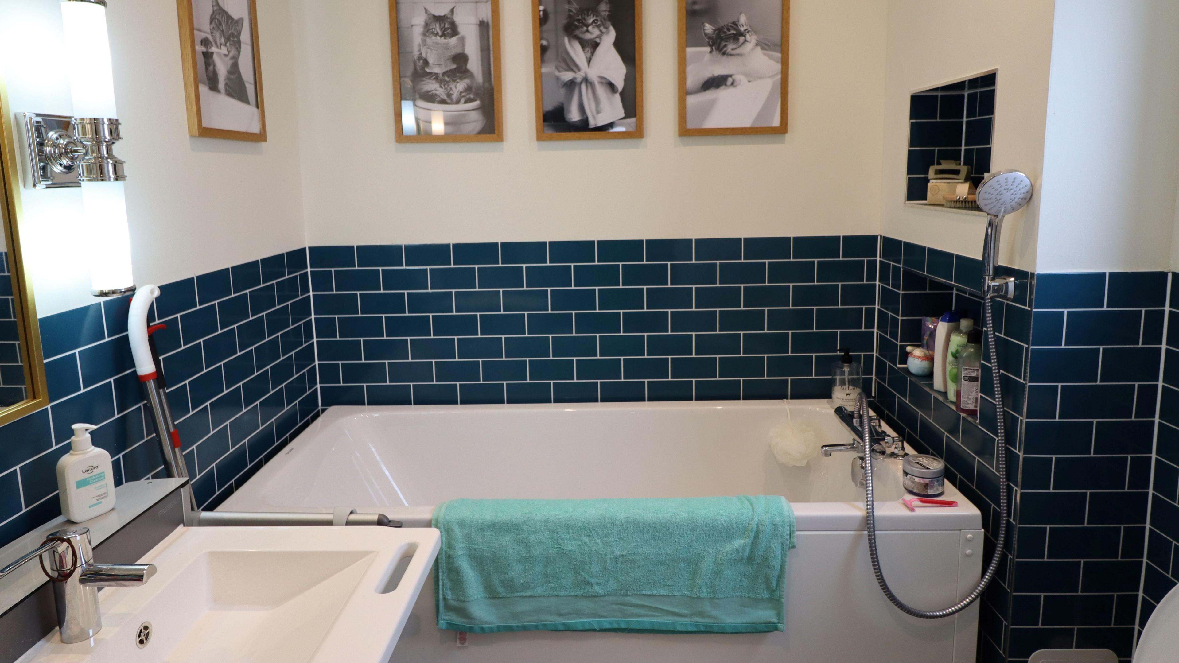 A white bath surrounded by navy blue tiles.