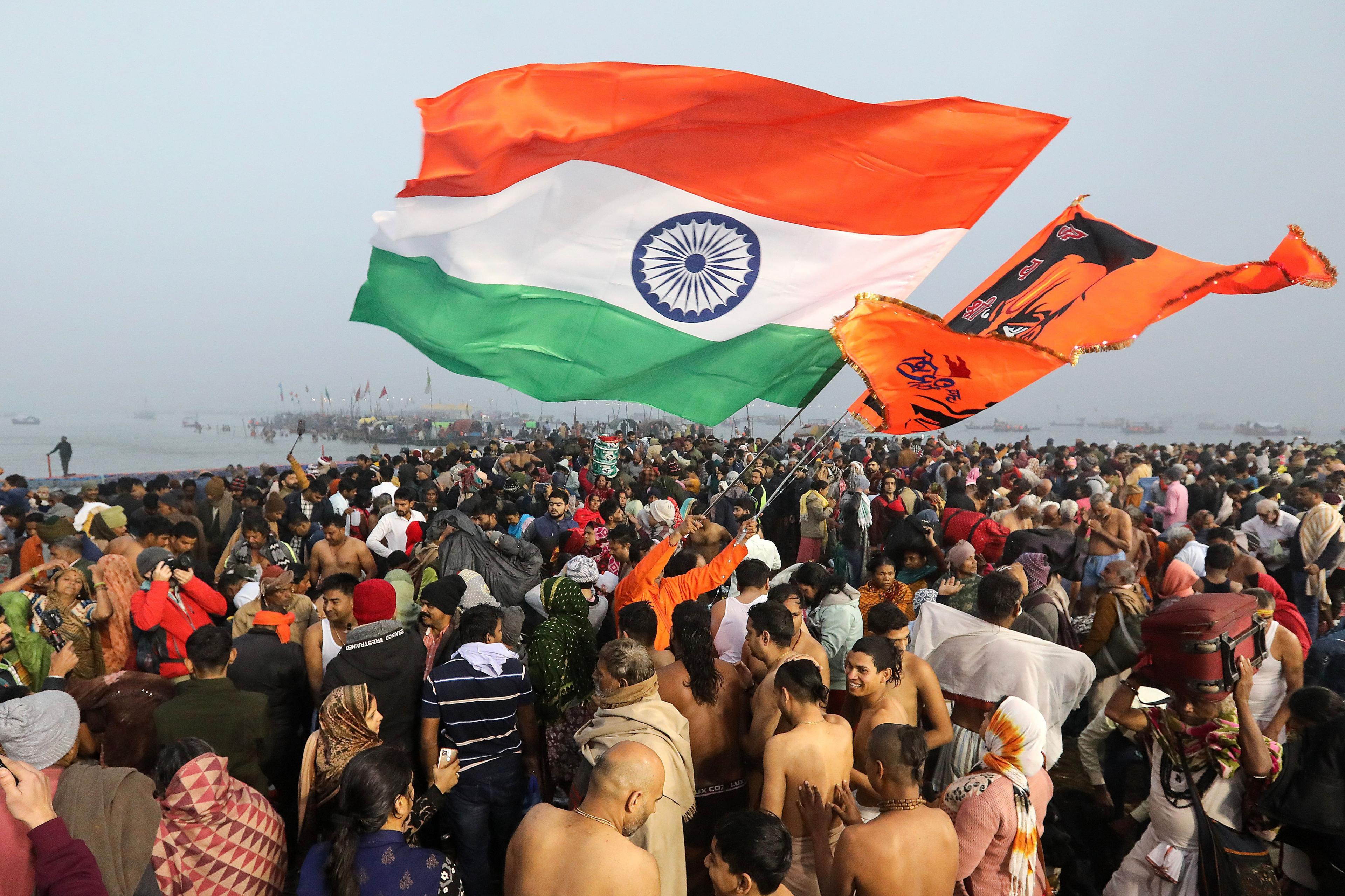 A man waves an Indian national flag as Hindu devotees gather to take a 'holy bath' on the first day of the Kumbh Mela festival.