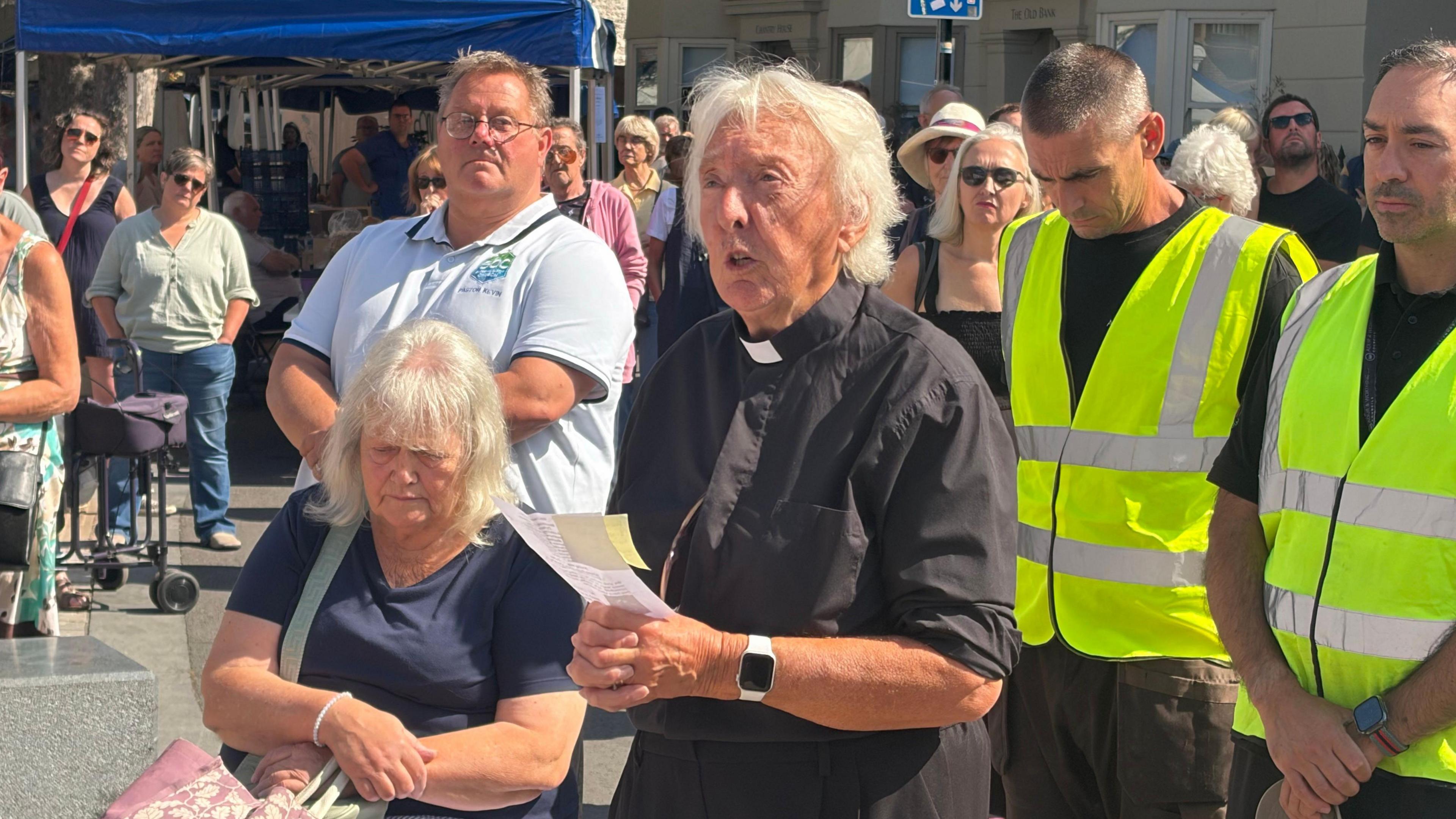 Reverend Pat Alden during the community vigil in Shoreham-by-Sea on 22 August. She is dressed in typical vicar attire and is holding a piece of paper.