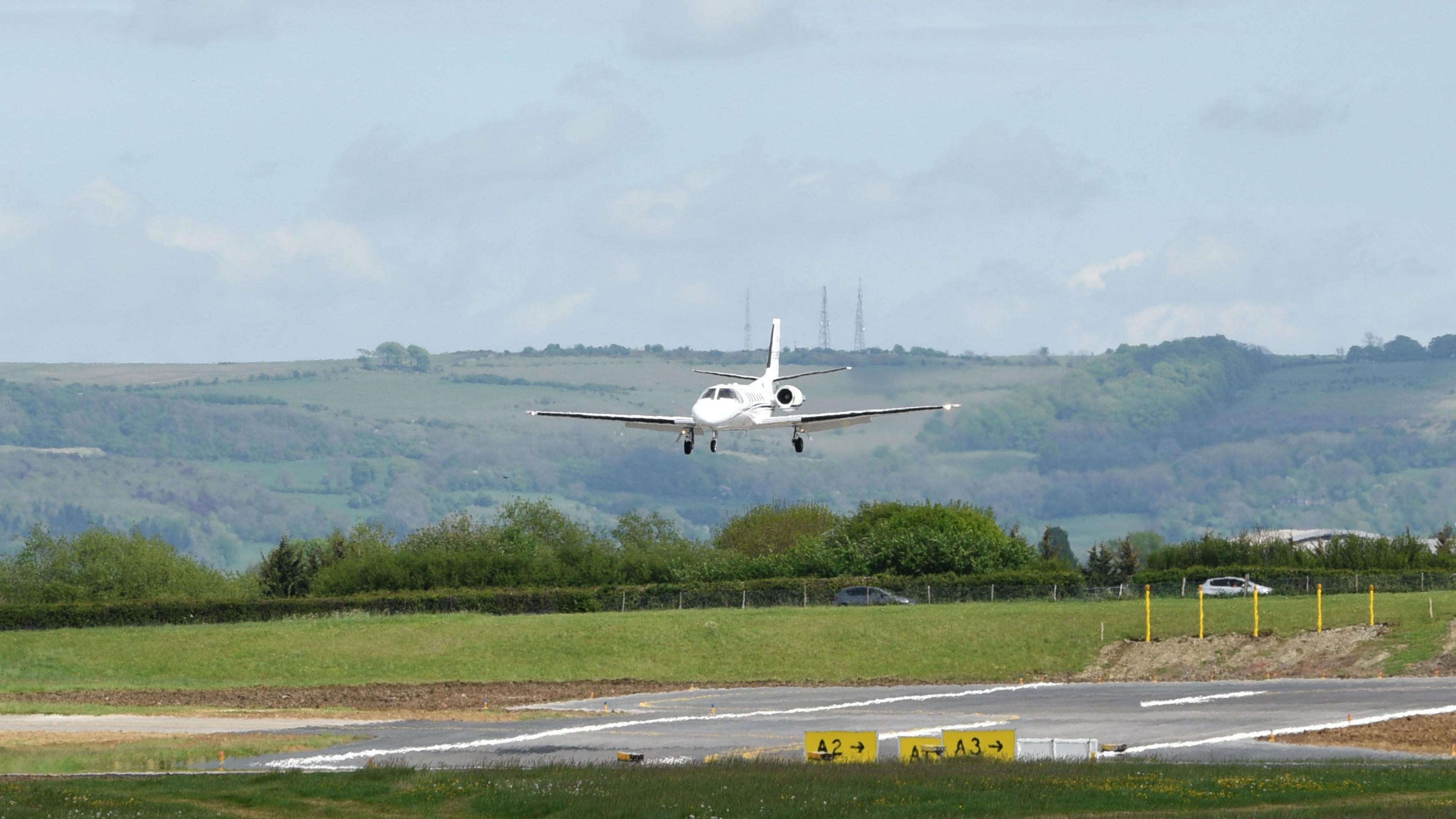 A small white plan landing at Gloucestershire Airport.