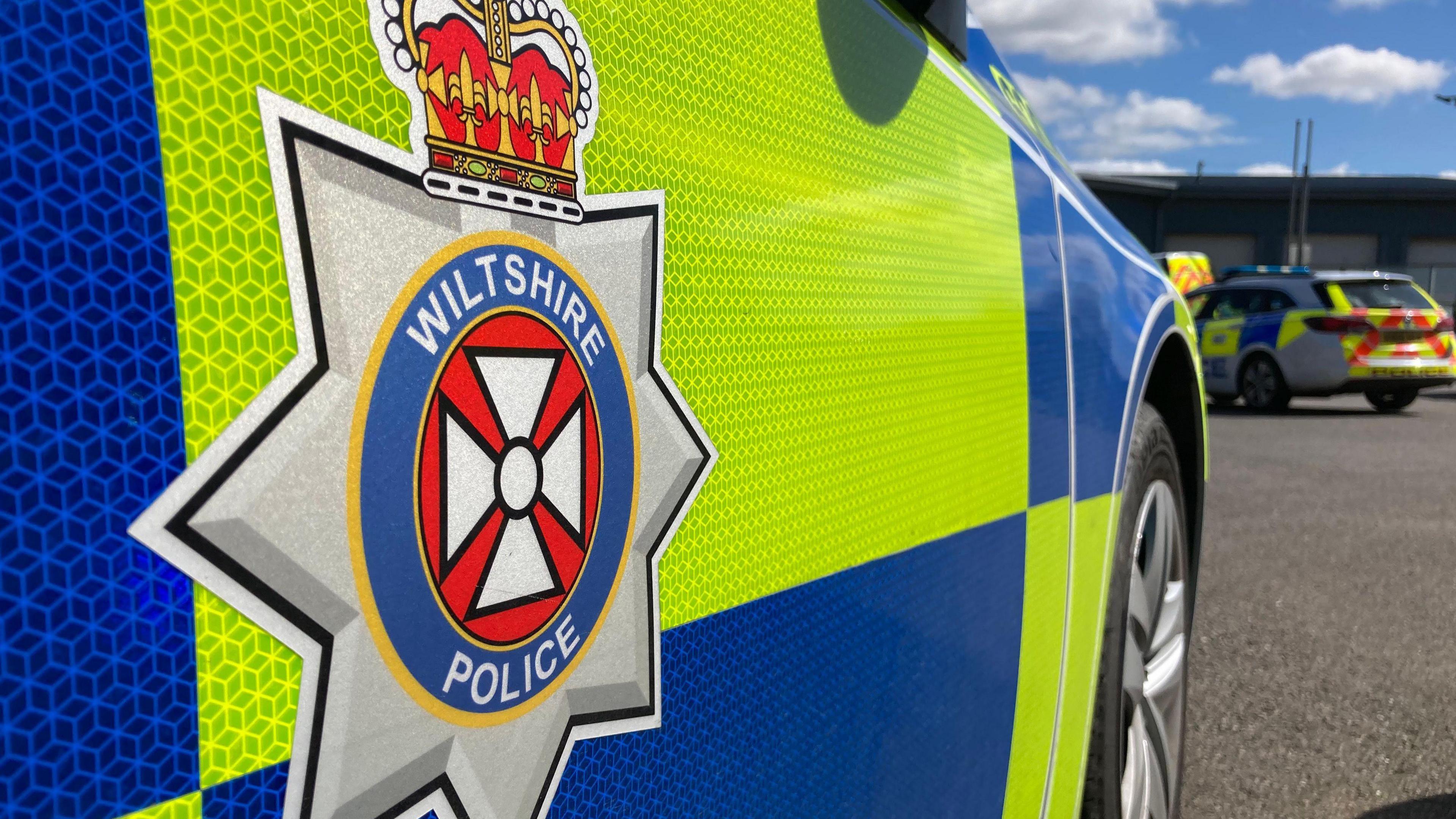 A high visibility police car with a Wiltshire Police emblem on the driver's door