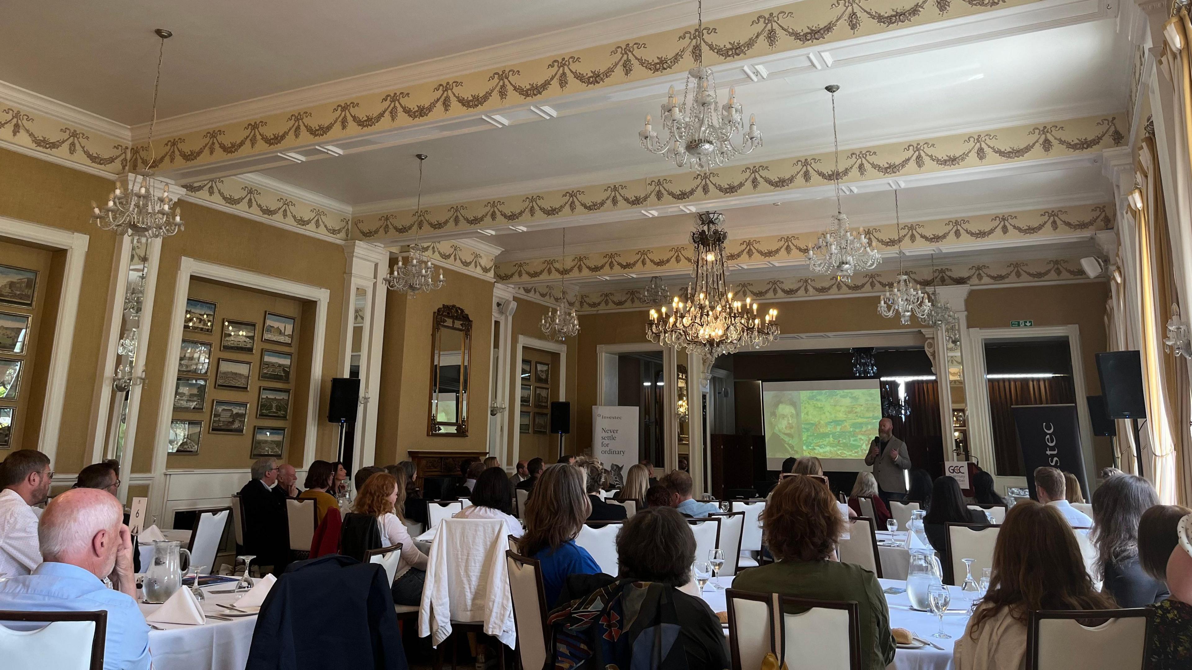 David Ummels presenting to people seated at tables in the Old Government House Hotel