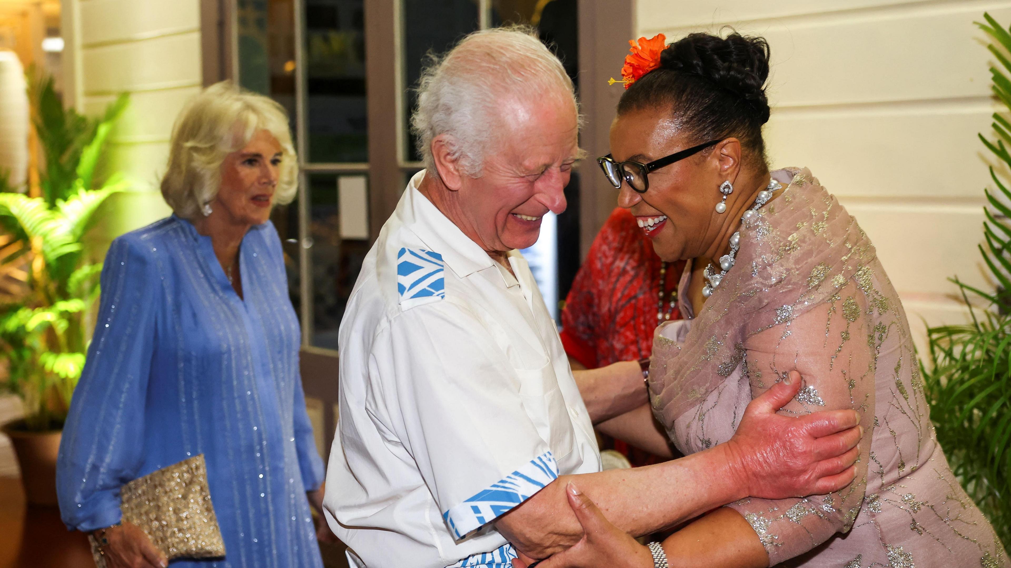 King Charles and Commonwealth Secretary General Patricia Scotland laugh as they embrace.
