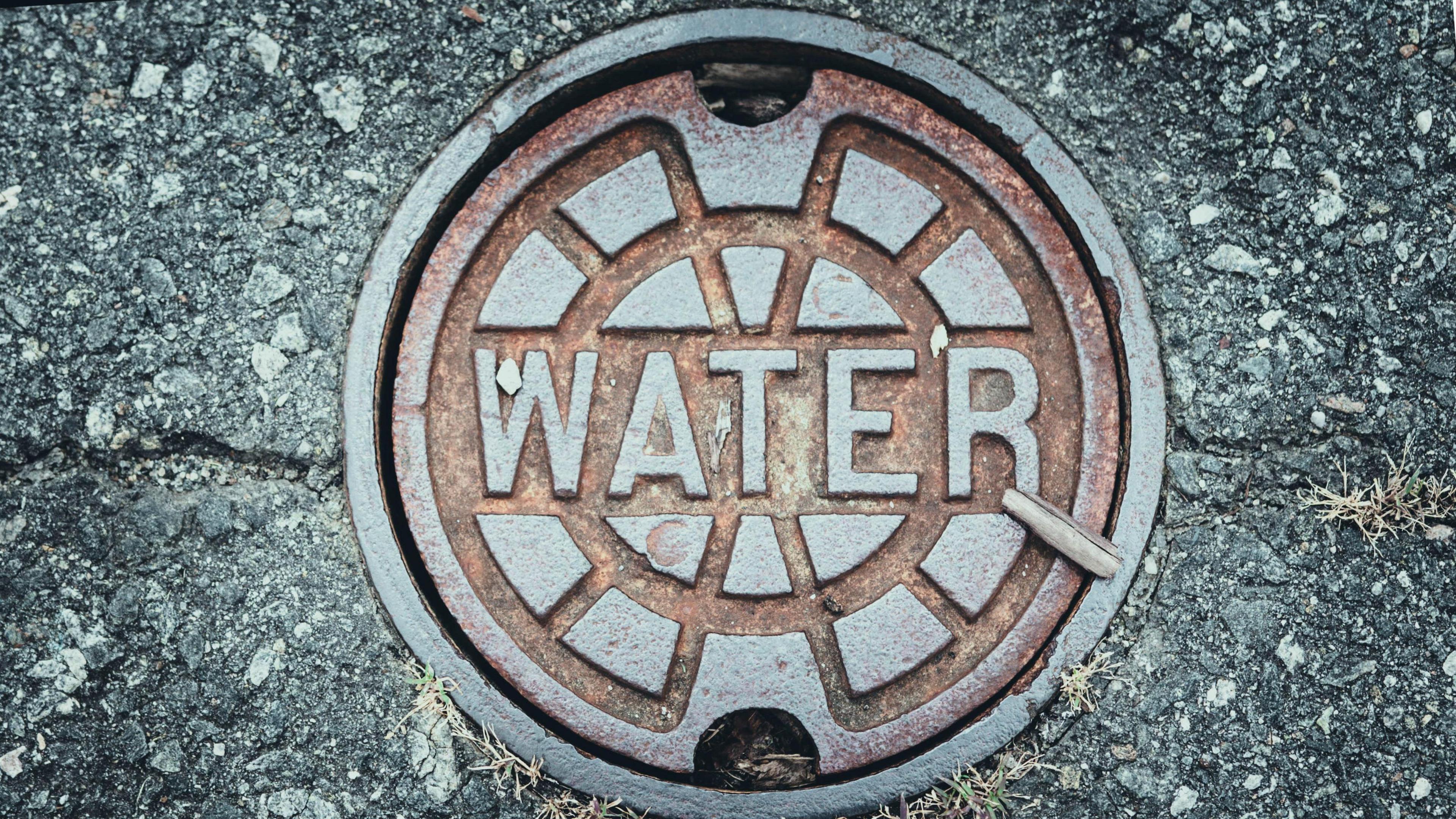 A metal water main cover on a road.