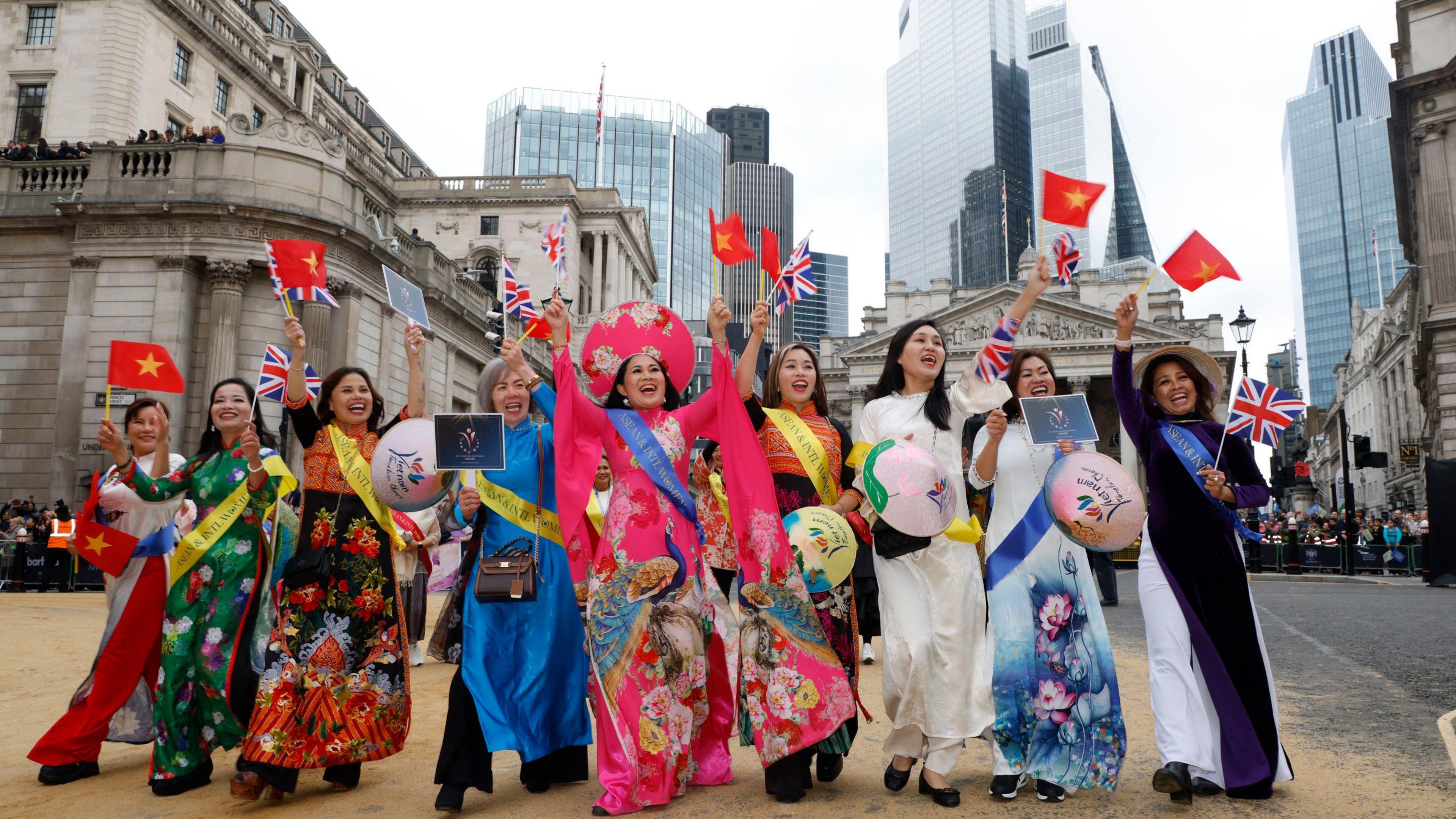 A group of women in traditional dress wave to crowds as they take part in the parade. 