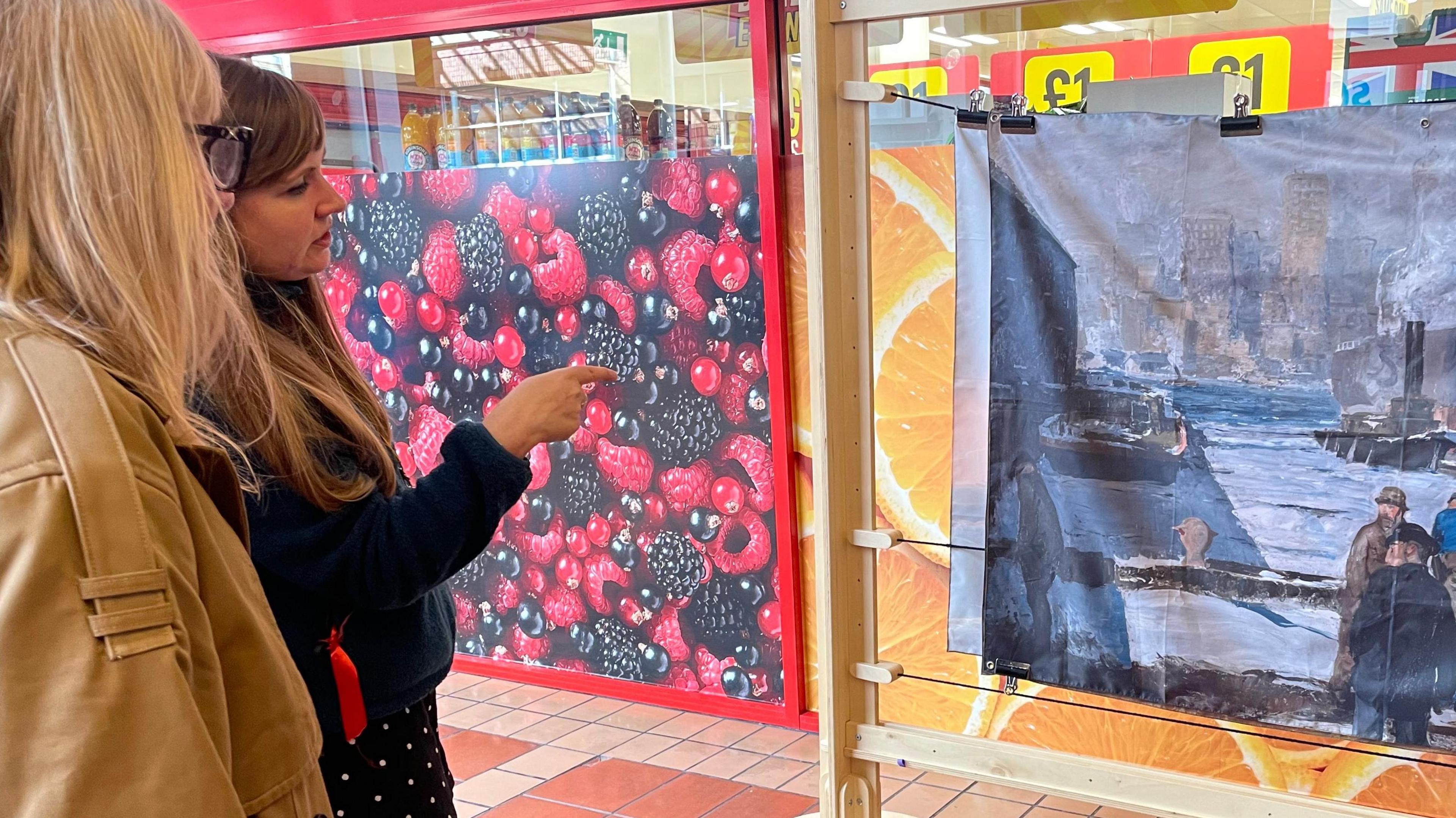 Two women stand looking at a painting in Angel Place in Bridgwater