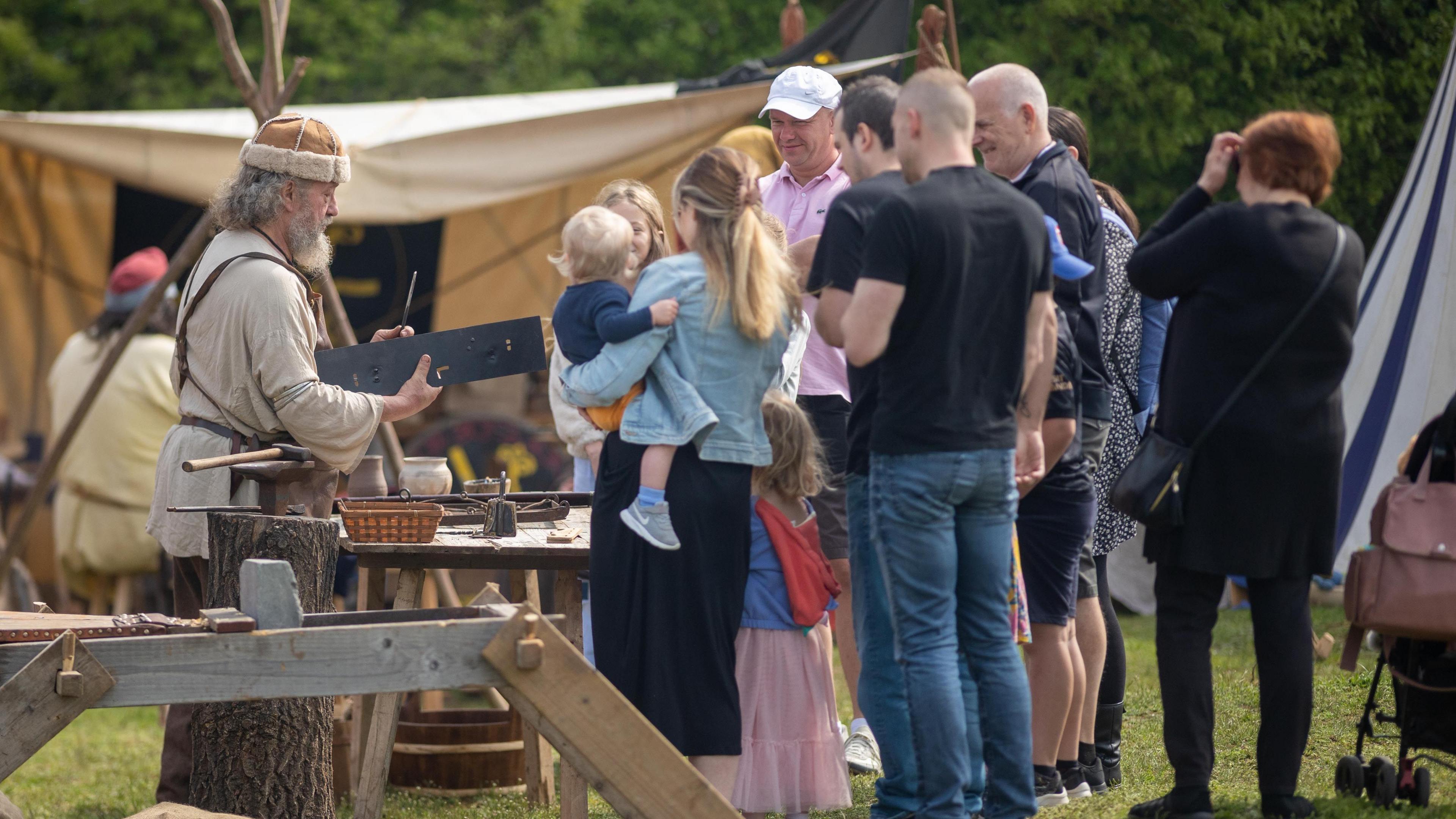 Crowds looking at Viking re-enactors making tools