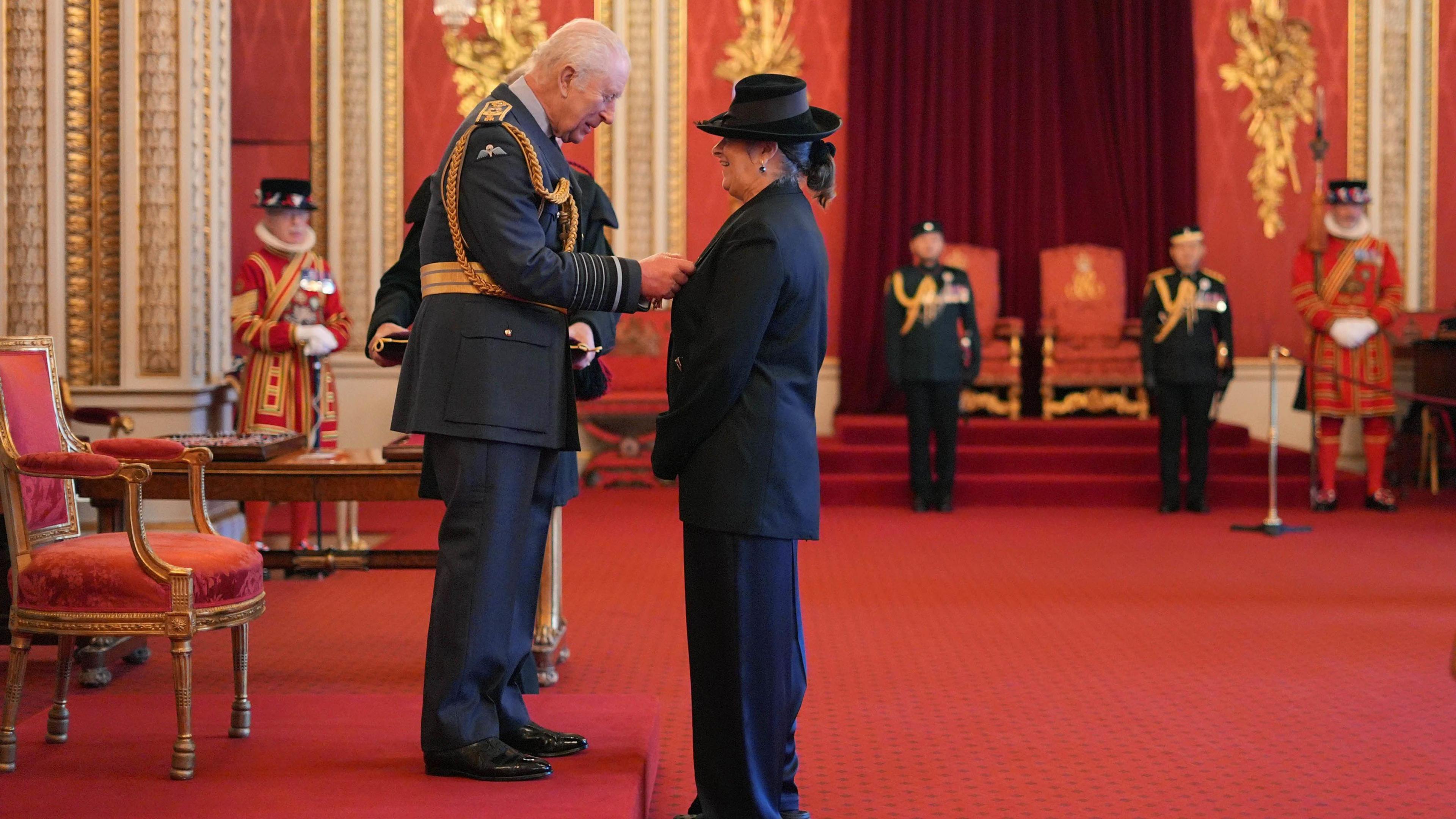 King Charles III puts a medal on Dame Tracey Emin as she receives her honour inside Buckingham Palace