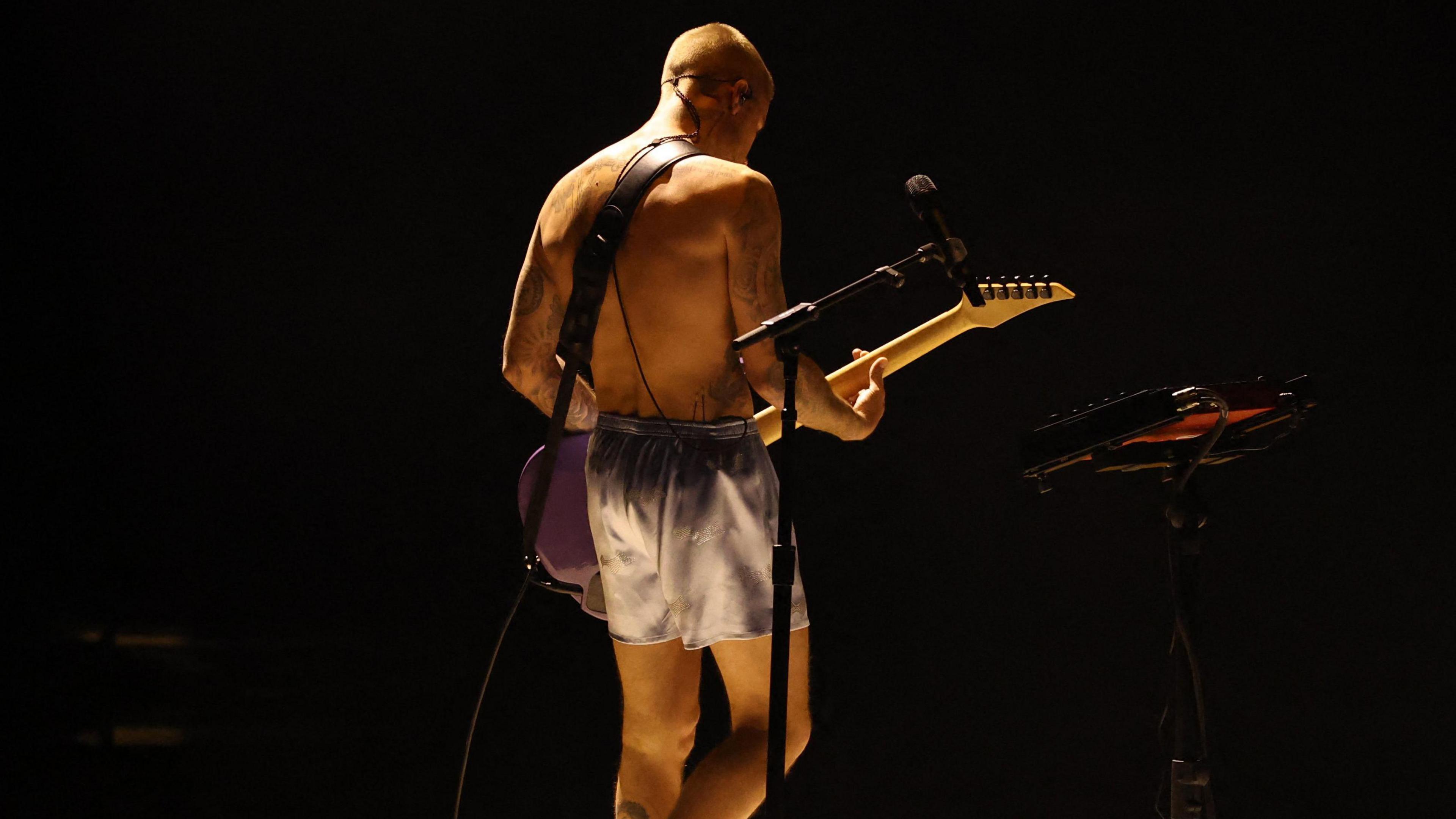Justin Bieber playing guitar in only his boxer shorts