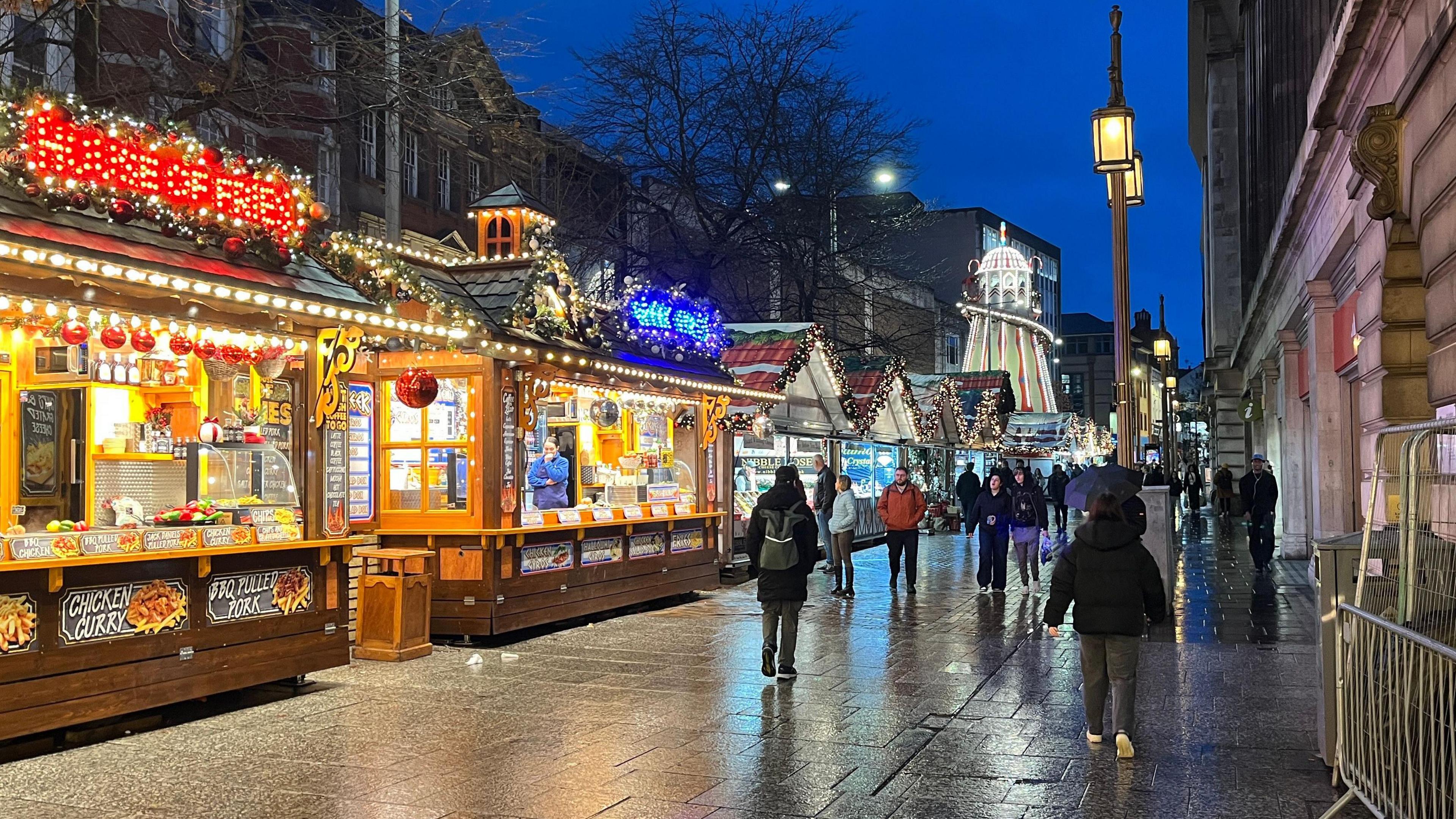 Series of stalls lining a city street, lit up at night