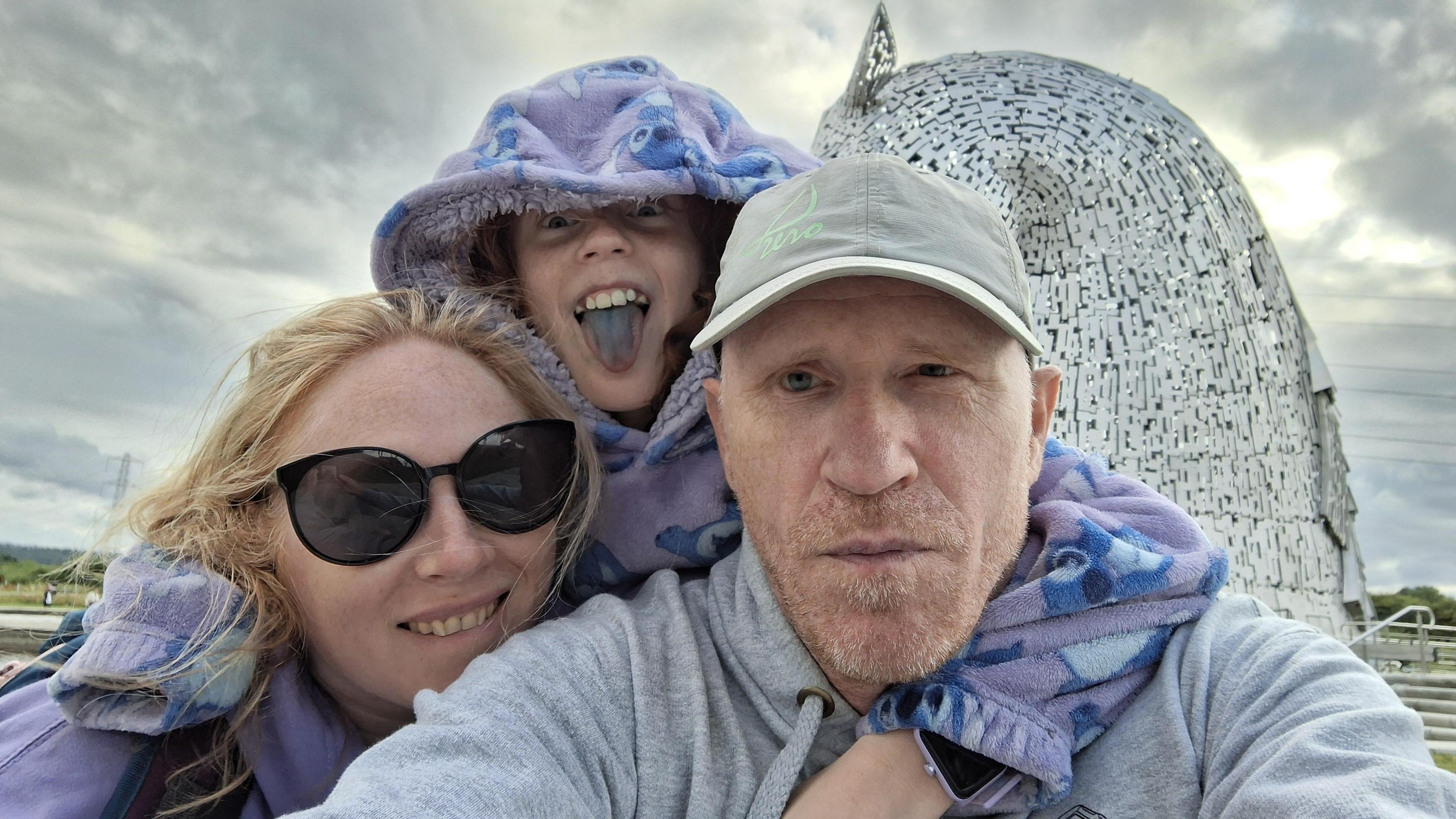 Paul Jefferies taking a selfie with his wife Fay and daughter Eirlys. They are wearing fleeces and hoodies, with Eirlys sticking her tongue out.