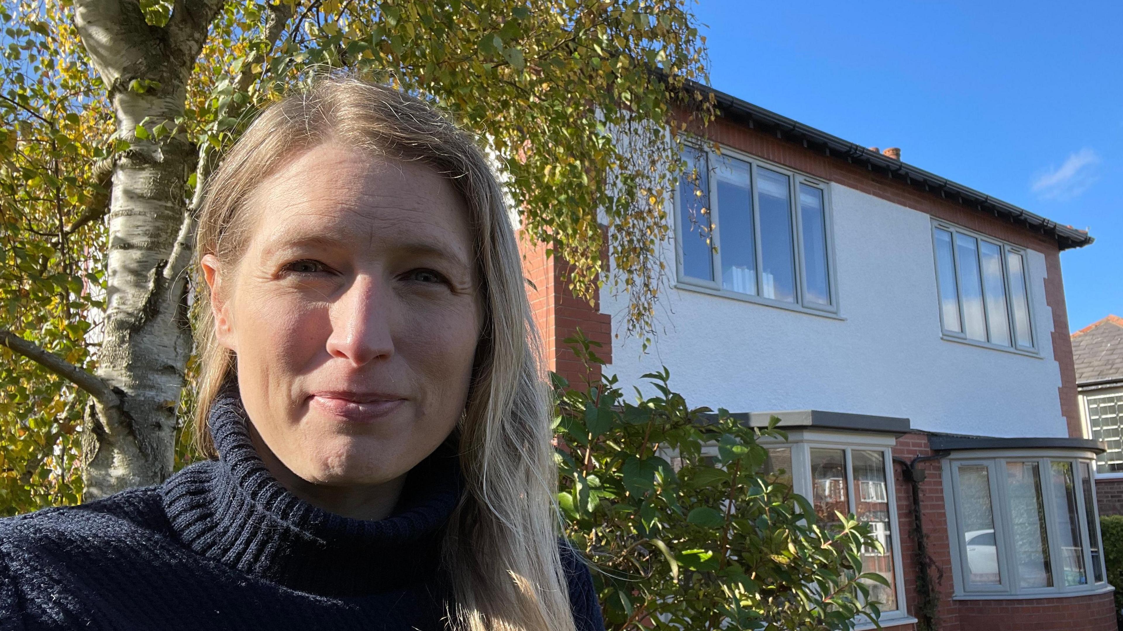 Amy Peace stands outside her house