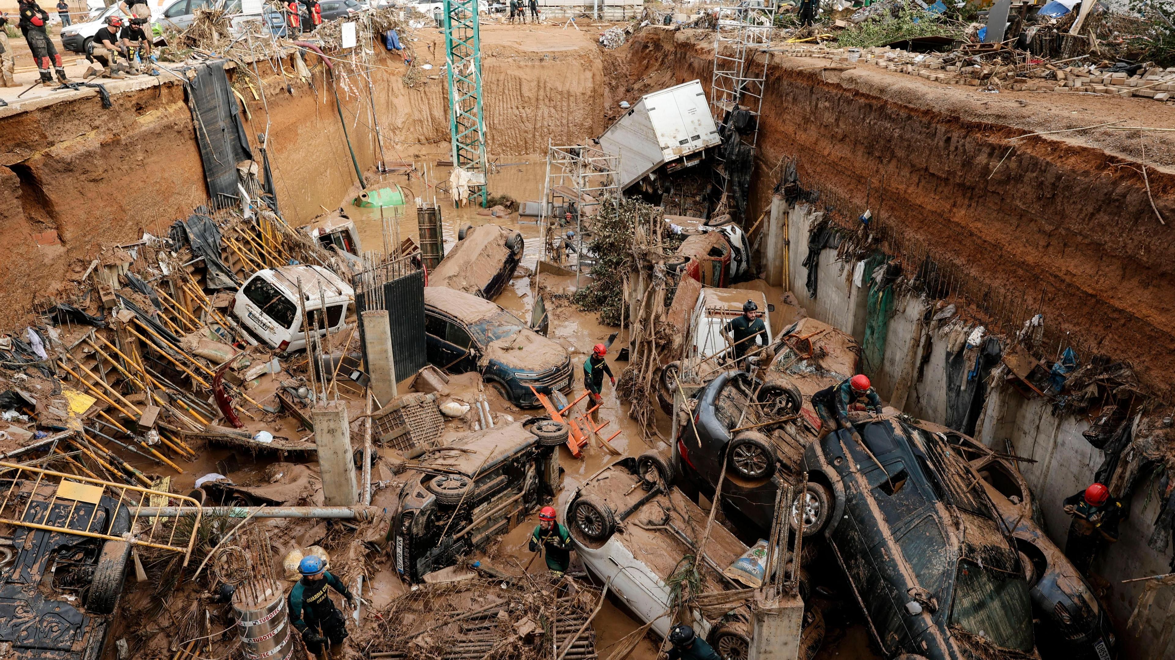 Civil Guard officers search for survivors inside cars trapped under the foundations of a building