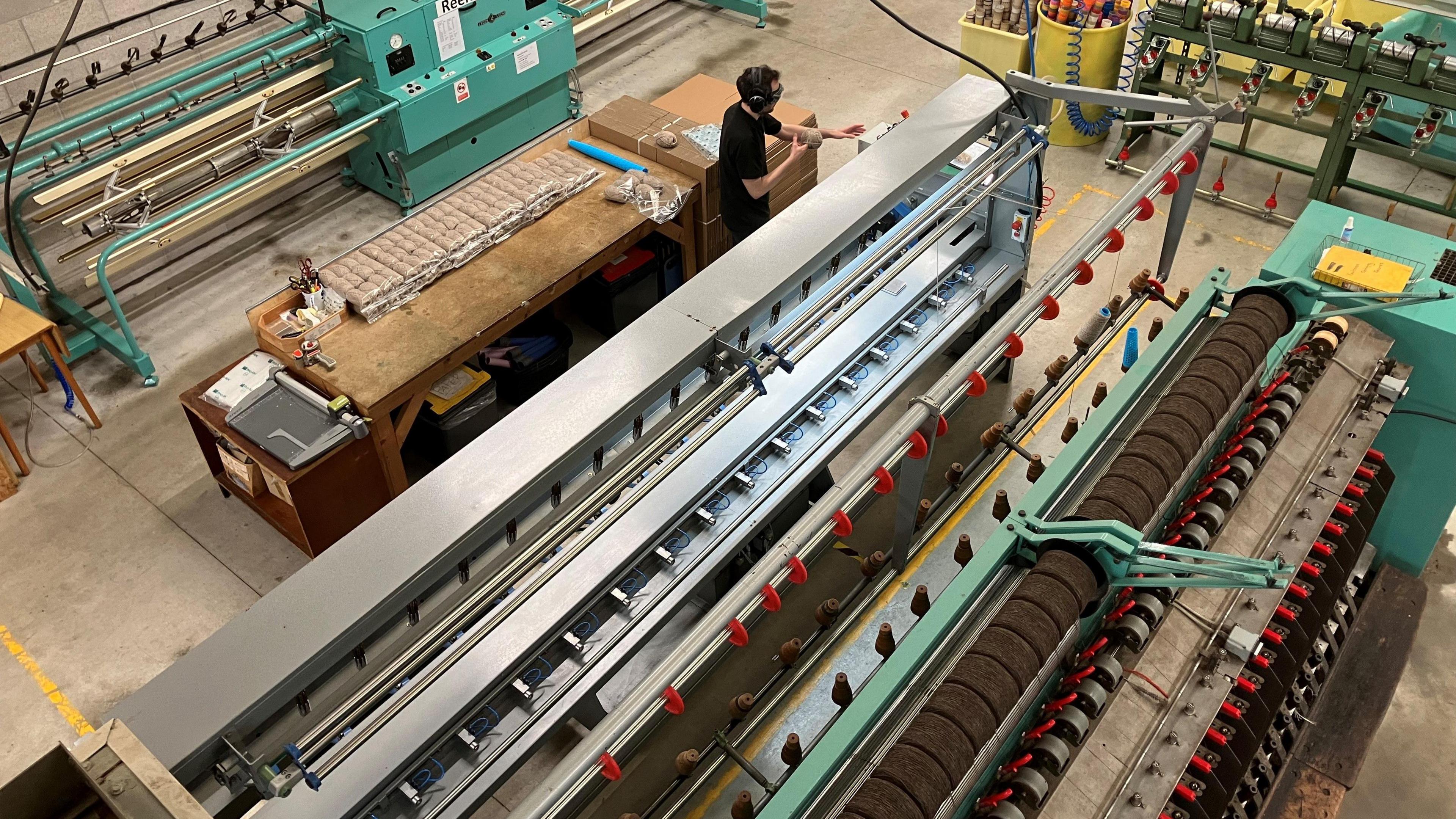 One man is working on the threading machines, which are large pieces of specialist machinery in a warehouse