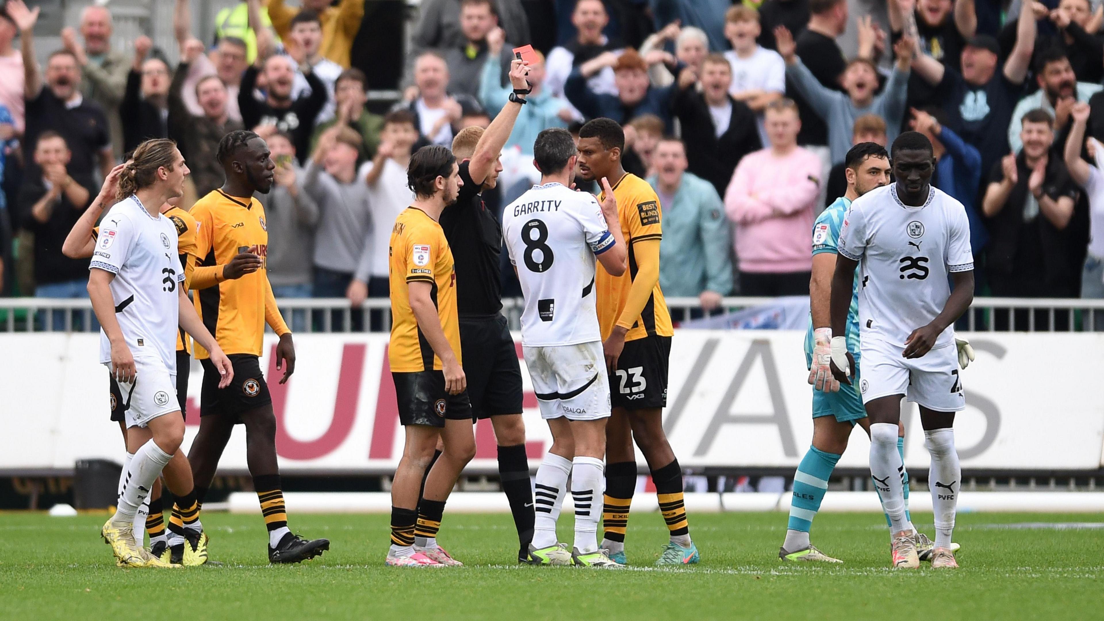 Kyle Jameson of Newport County is shown a red card