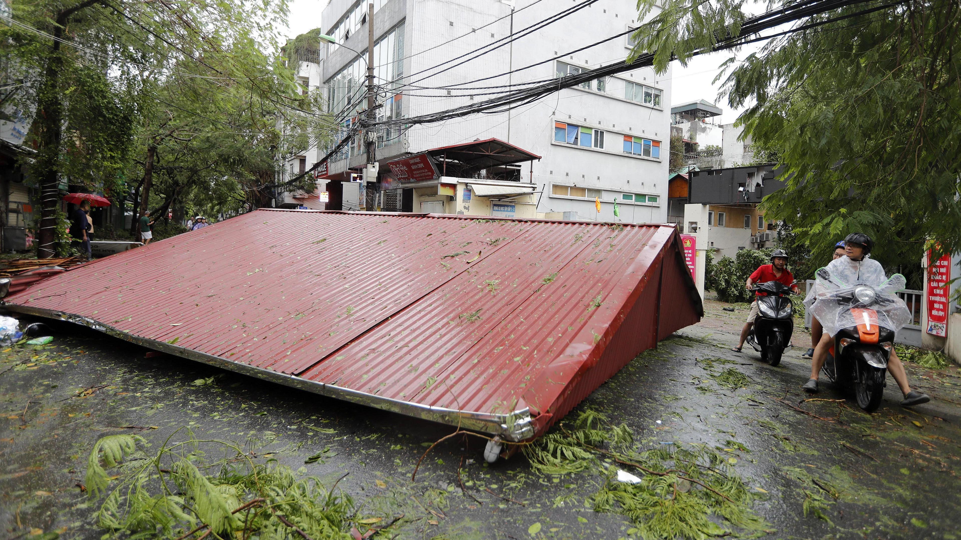 A metal roof is seen on the street after strong winds blew it off the property