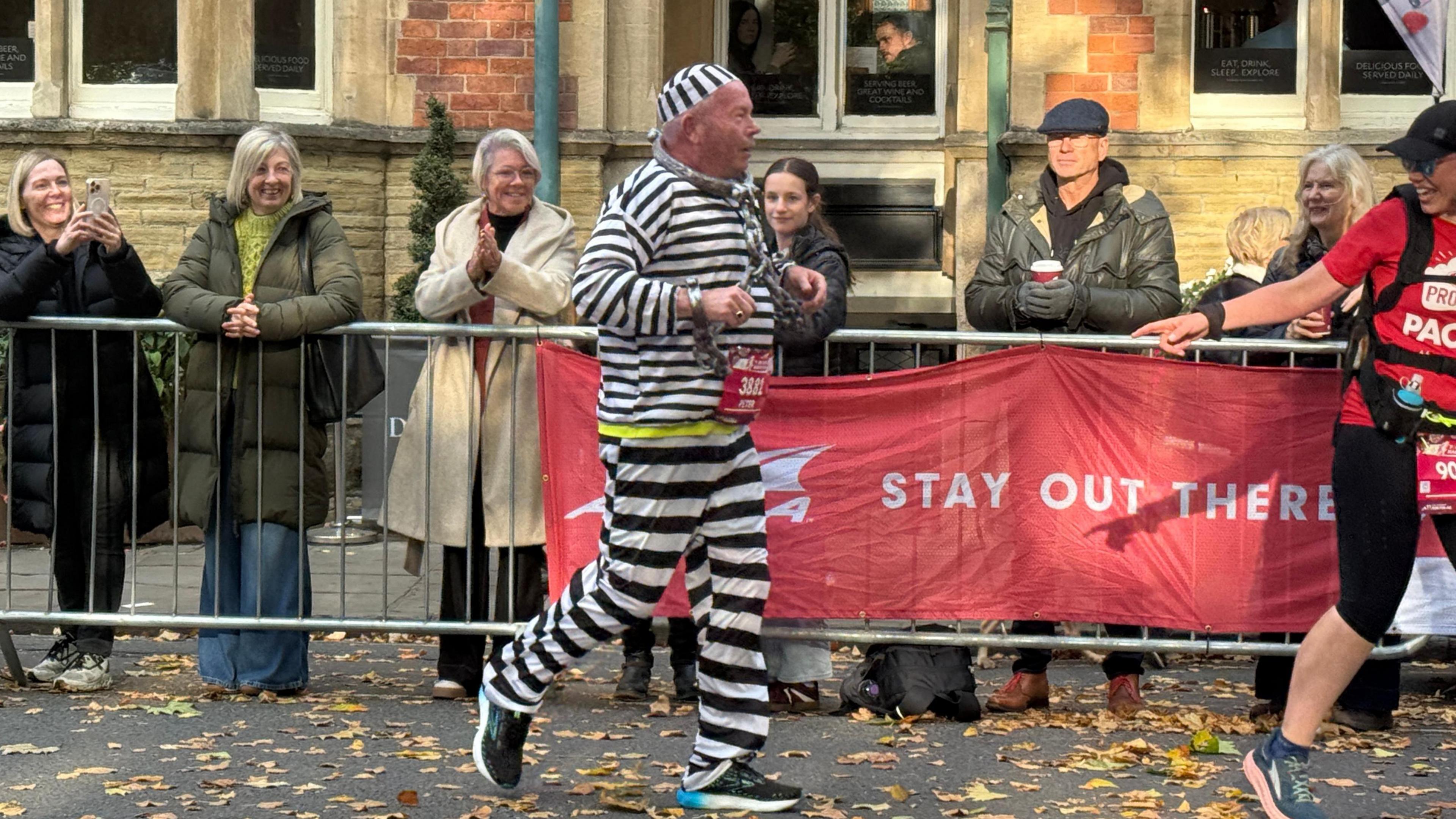 Man running in prisoner fancy dress costume