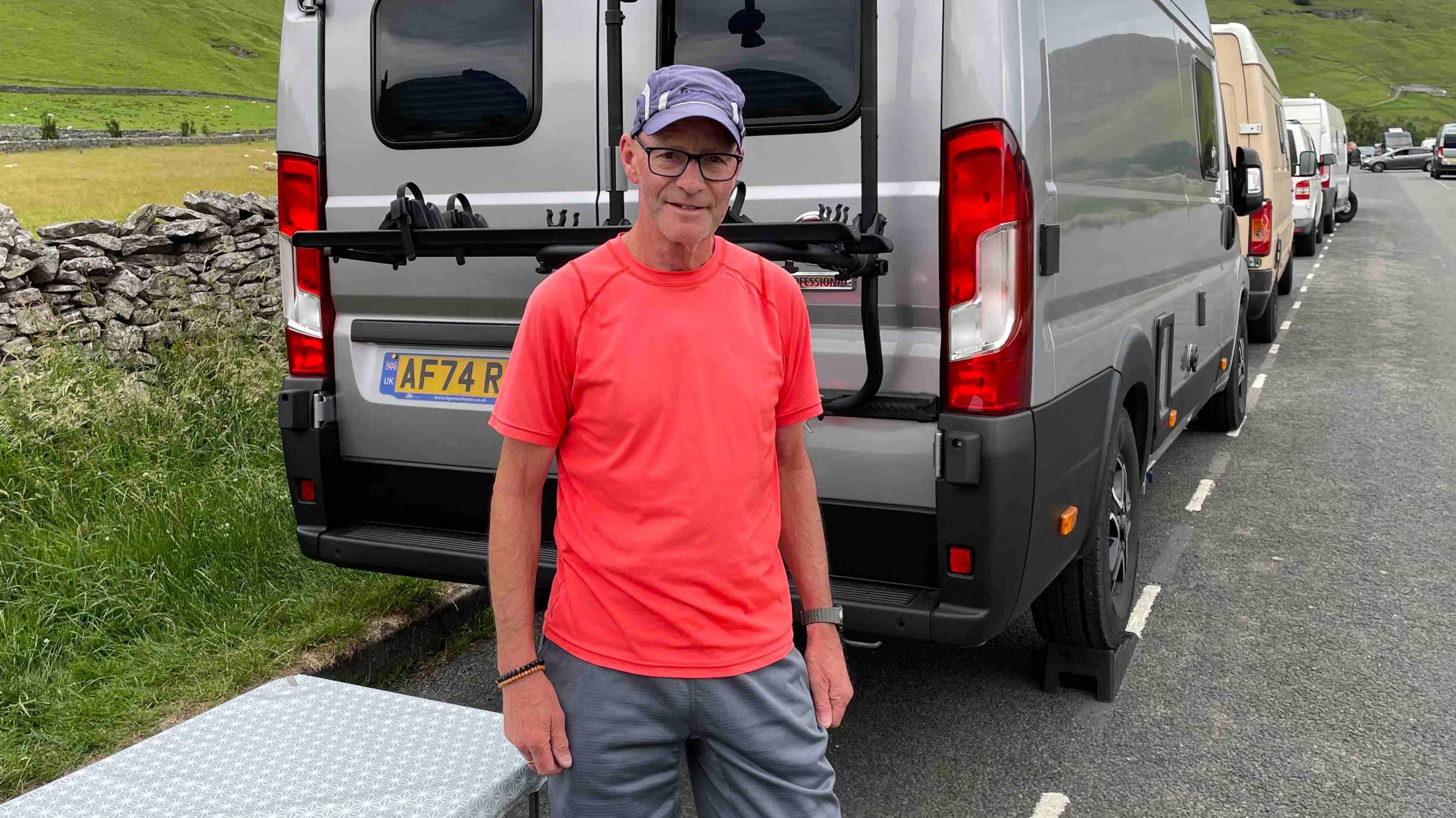 Man stood near campervan in bright orange t-shirt