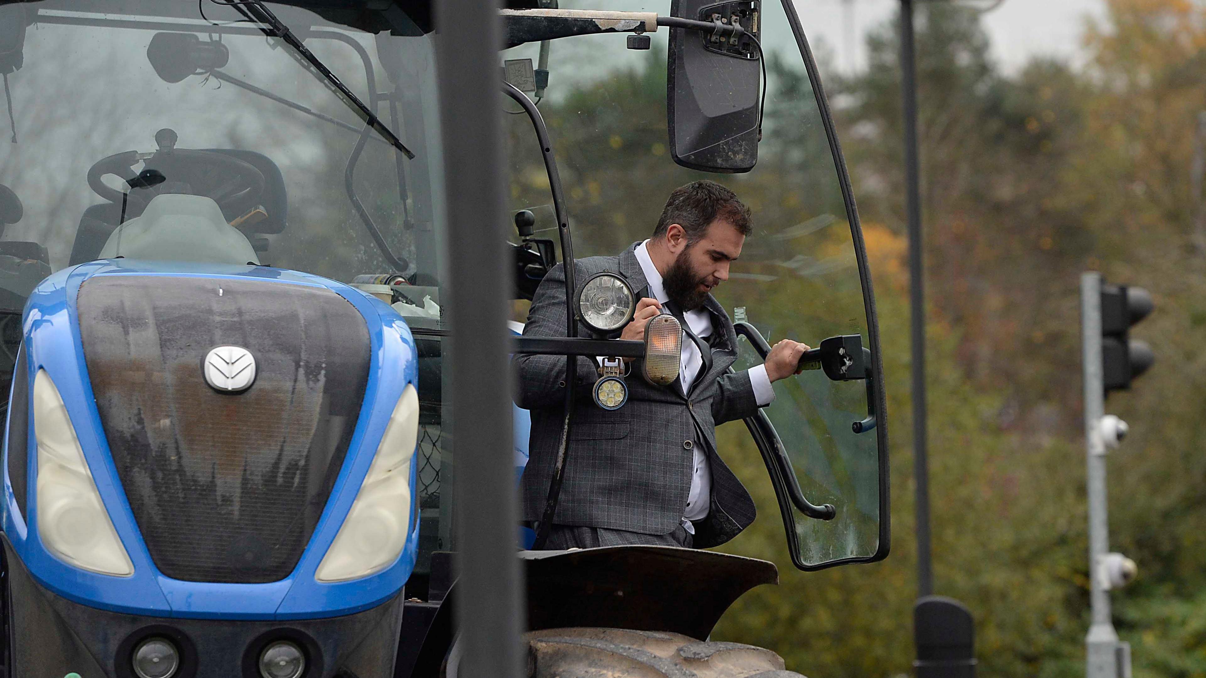 a man in a grey suit stepping out of a tractor