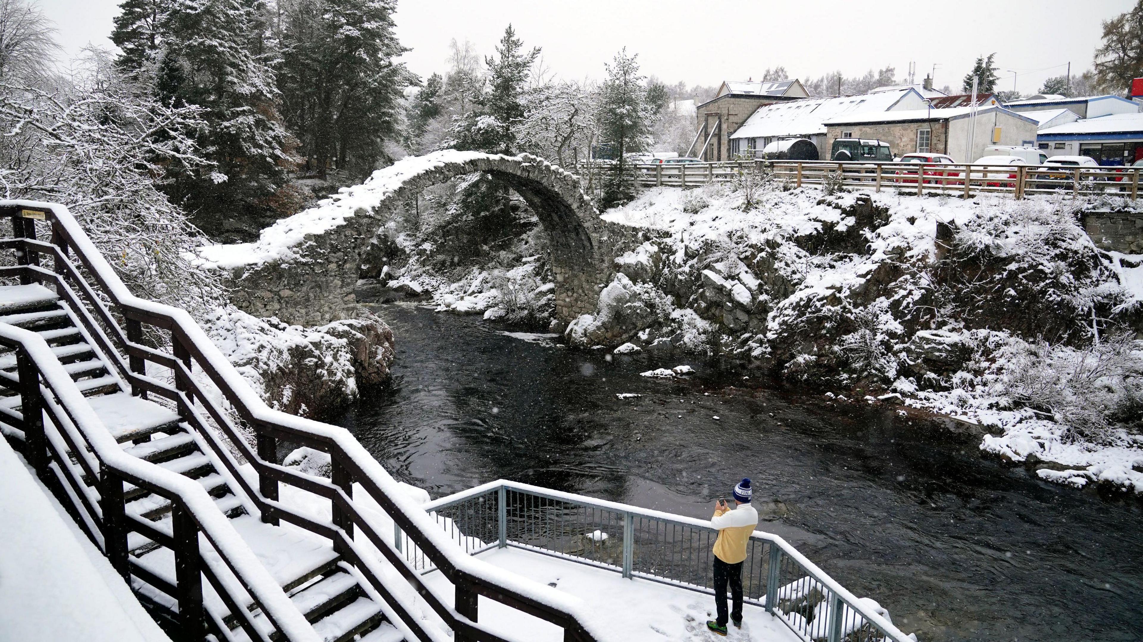 Snow over a bridge and on either side of a river 