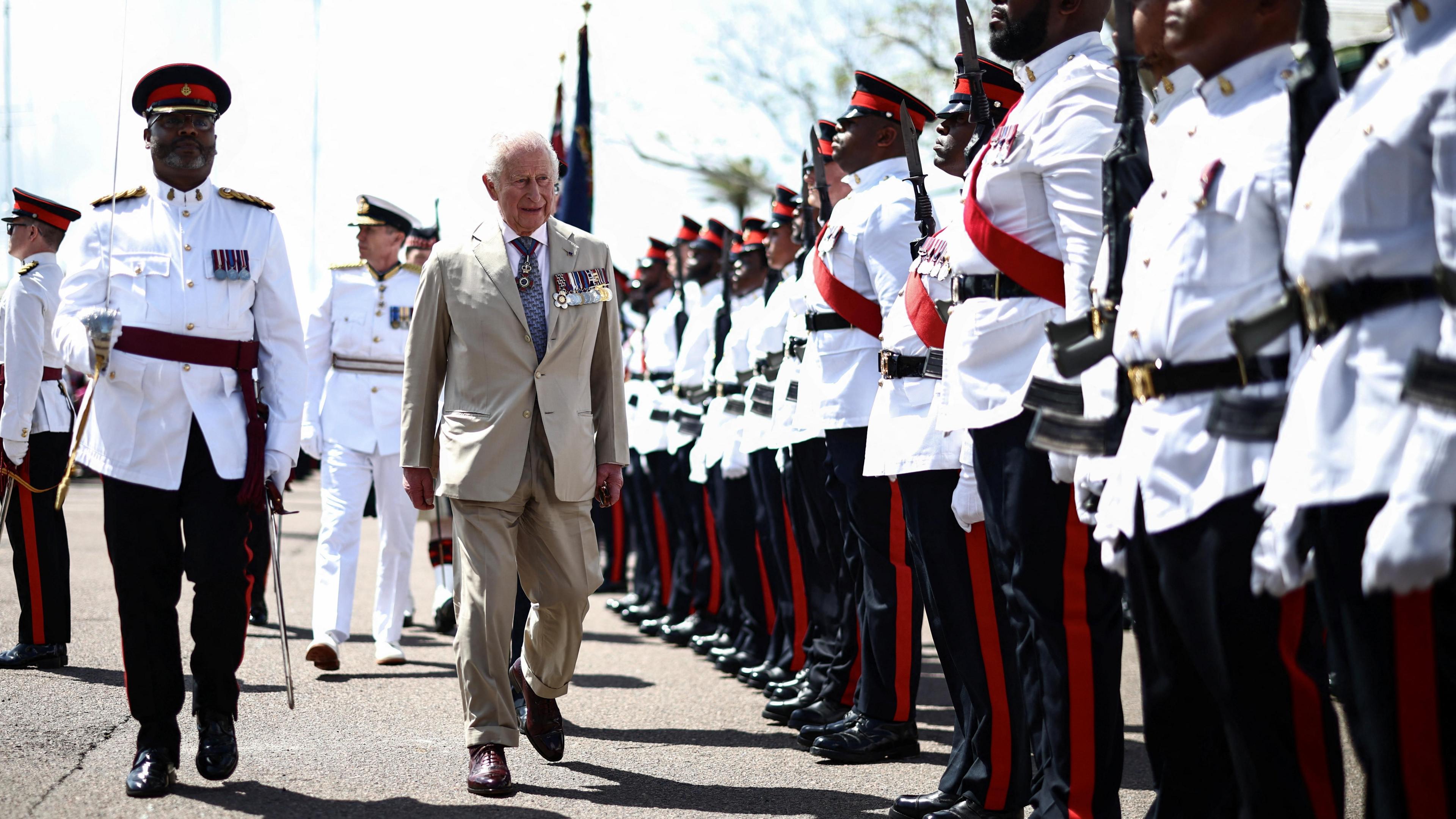 Mbreti Charles III i veshur me një kostum ngjyrë bezhë me medalje ushtarake, ecën pranë një rreshti të gjatë trupash të Regjimentit Mbretëror të Bermudës
