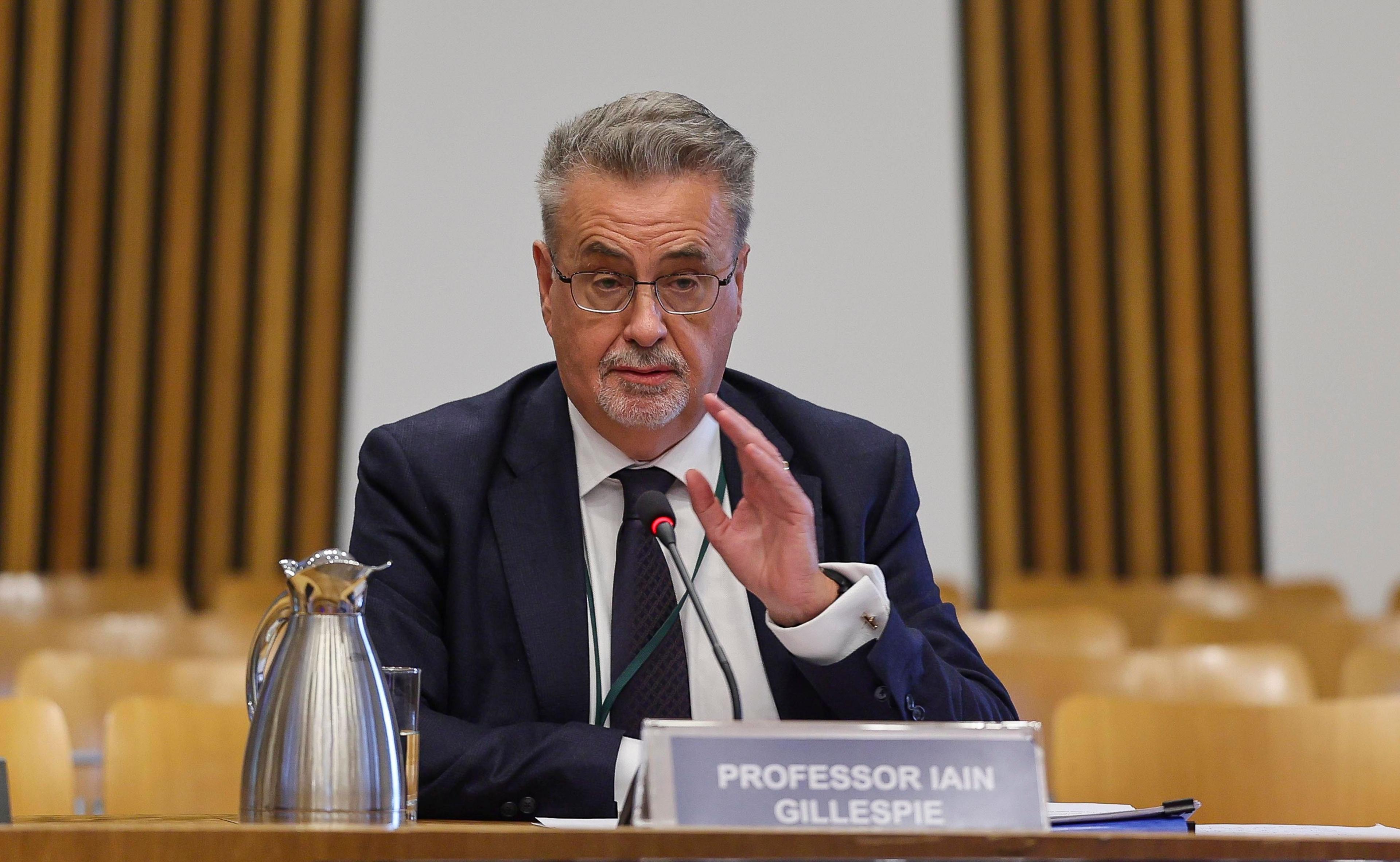 A man wearing a suit and tie speaks to a committee