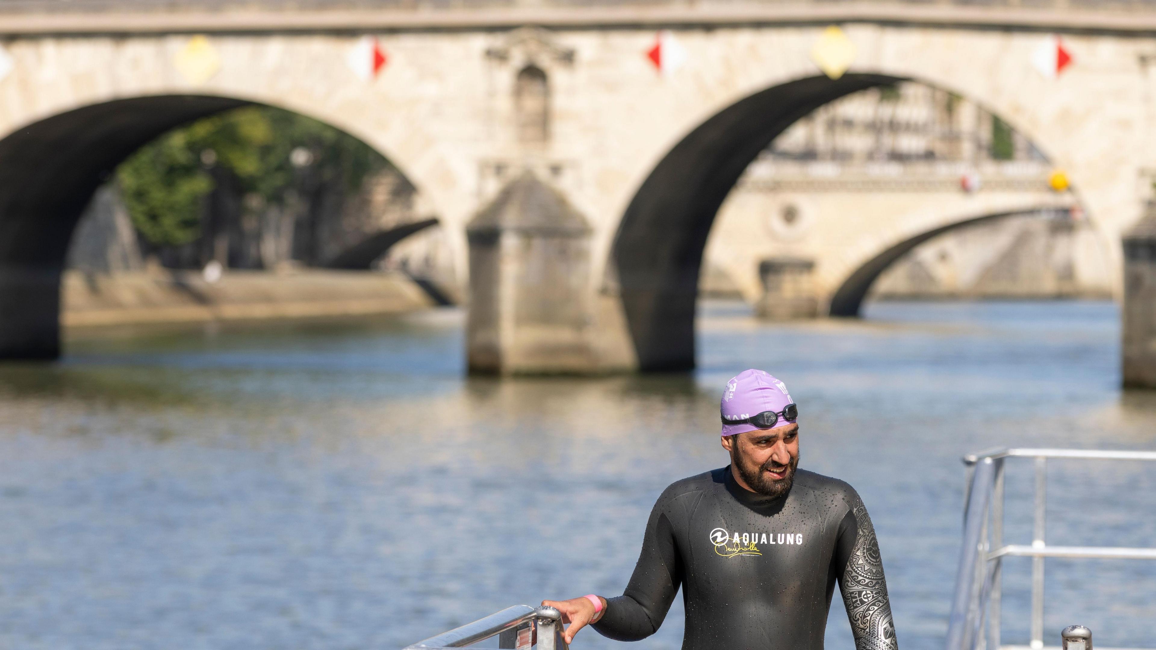 A swimmer climbs out of the River Seine after swimming there