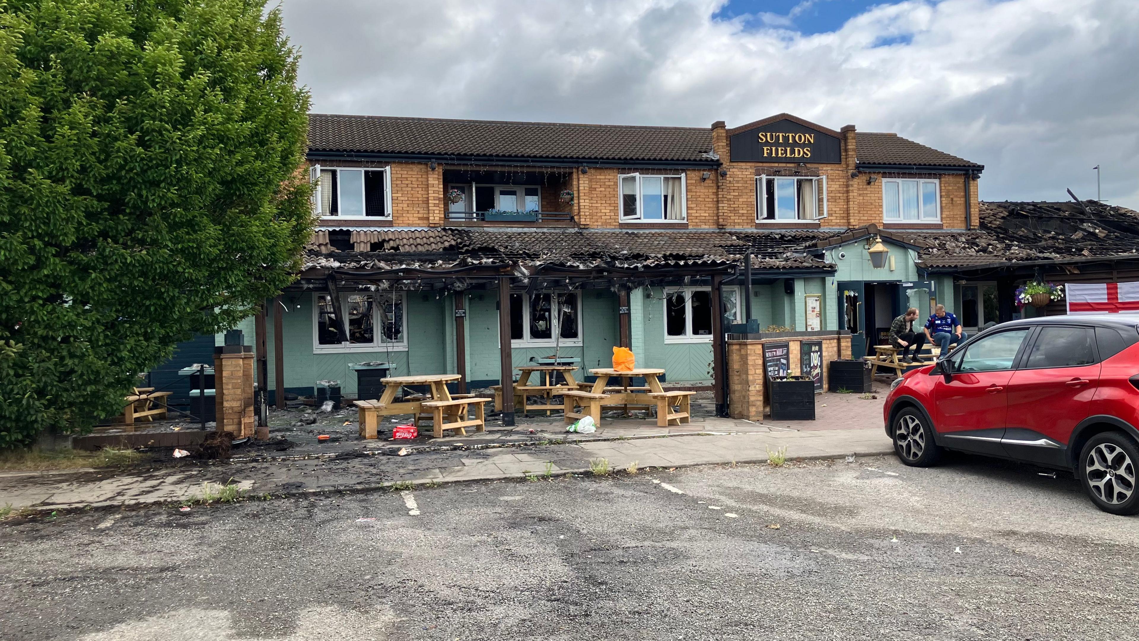 The 1970s style building has two floors, with a tiled wraparound porch around the first floor. The tiles and porch are black and the tiles have been badly damaged. The roof on an extension to the right of the building has been badly damaged.