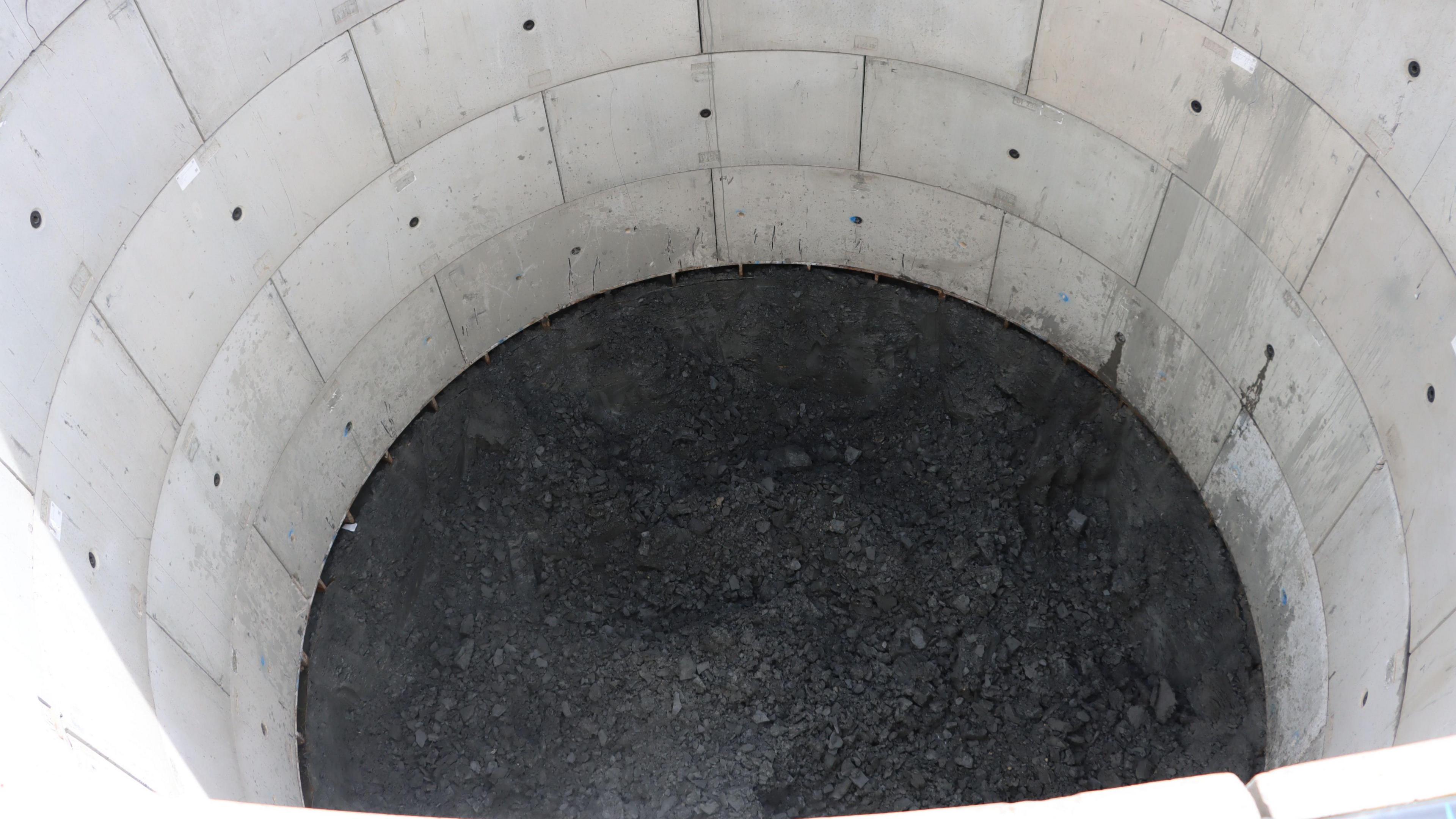 View looking into the tank. It looks like a large concrete well with a black base. 