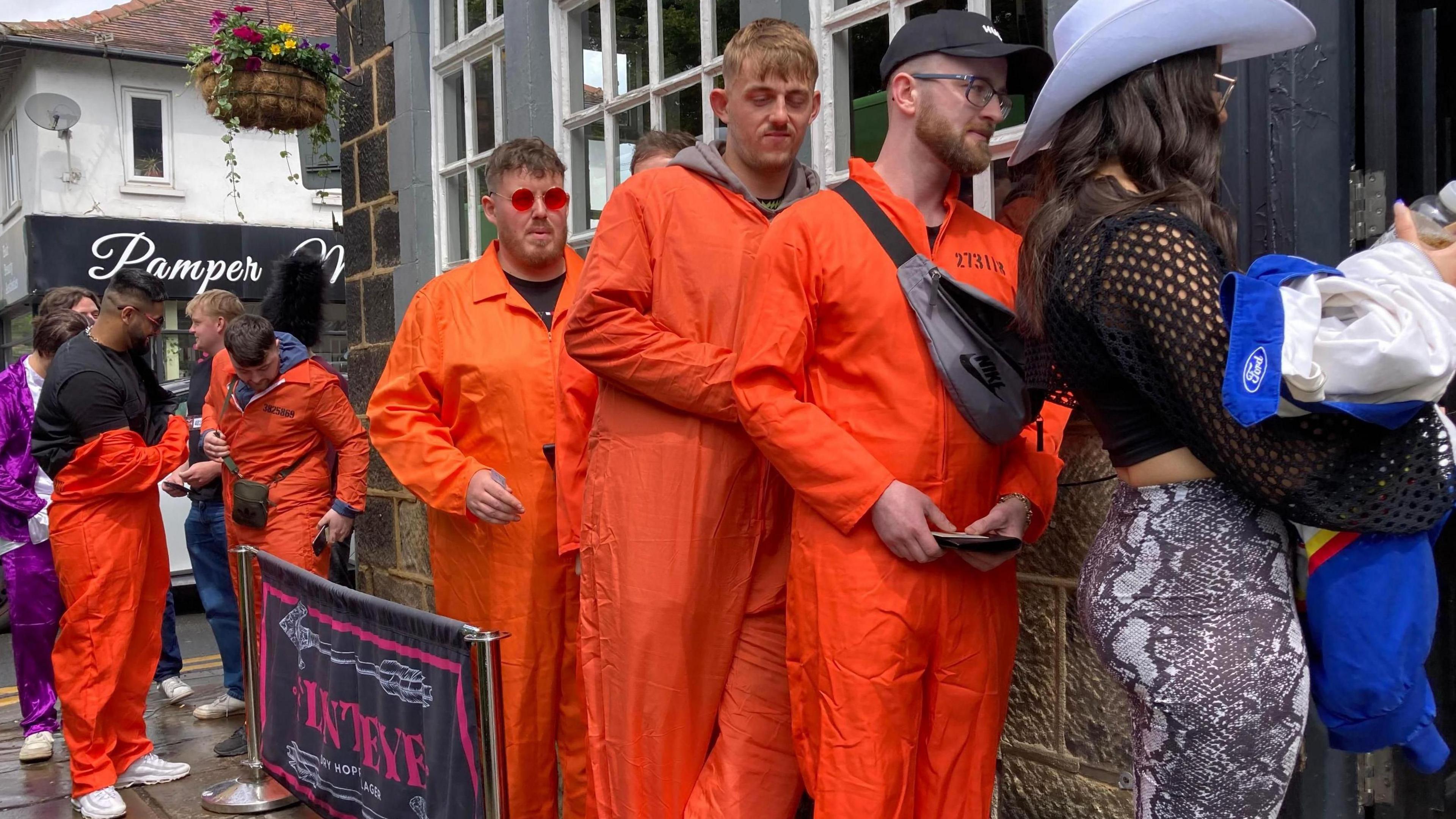 Several people wearing fancy dress queue to get in a pub.