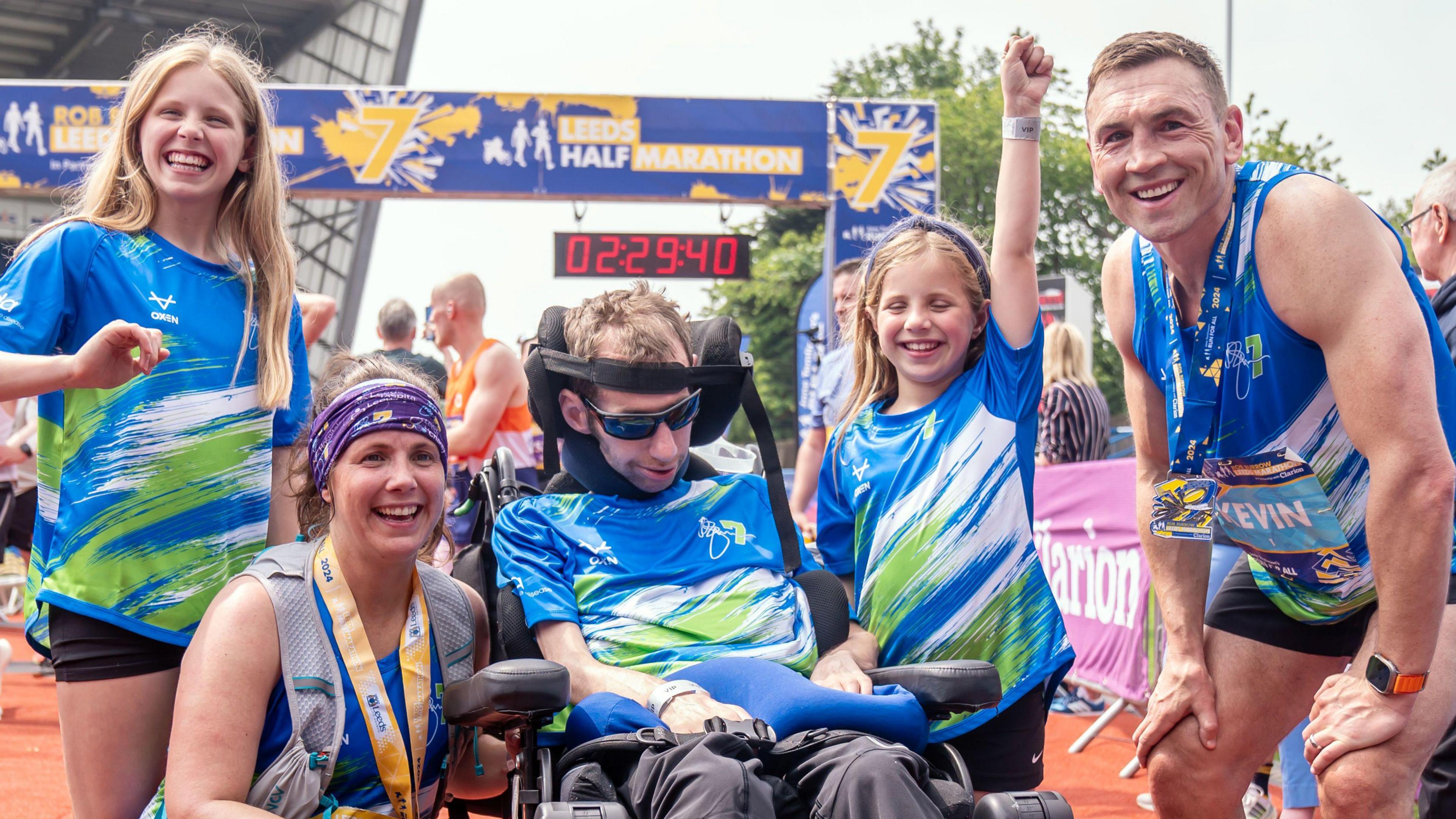 Group picture of Rob Burrow in his MND wheelchairwith his wife, two daughters and Sinfield at the finsih line of the Rob Burrow Leeds Marathon in 2024