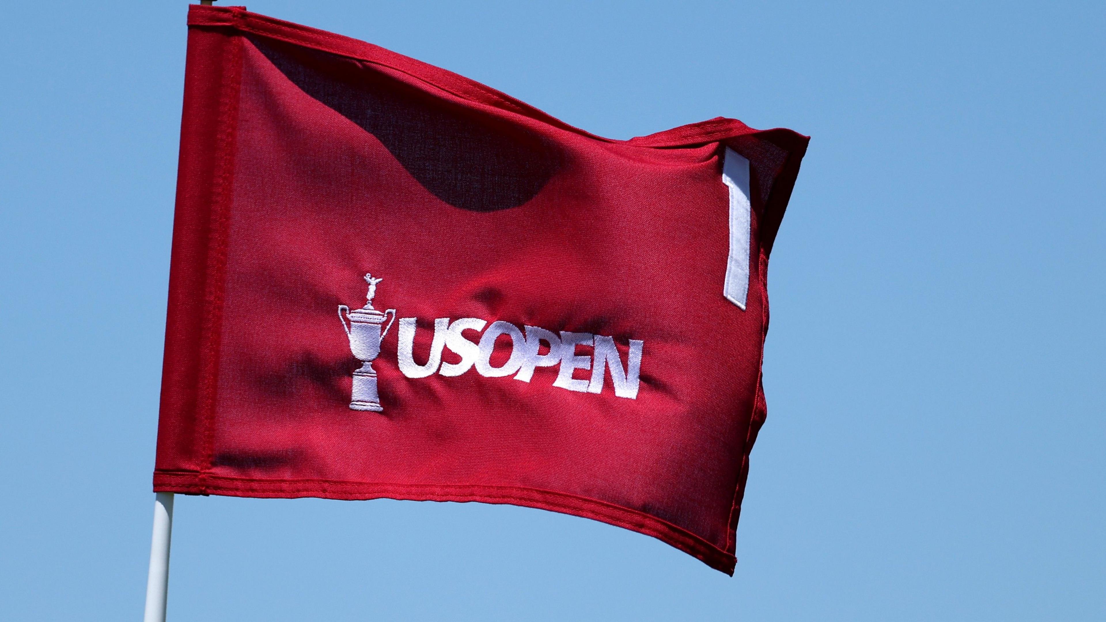 A red flag with an image of the US Open trophy, the words US Open and the number one on it, all in white.