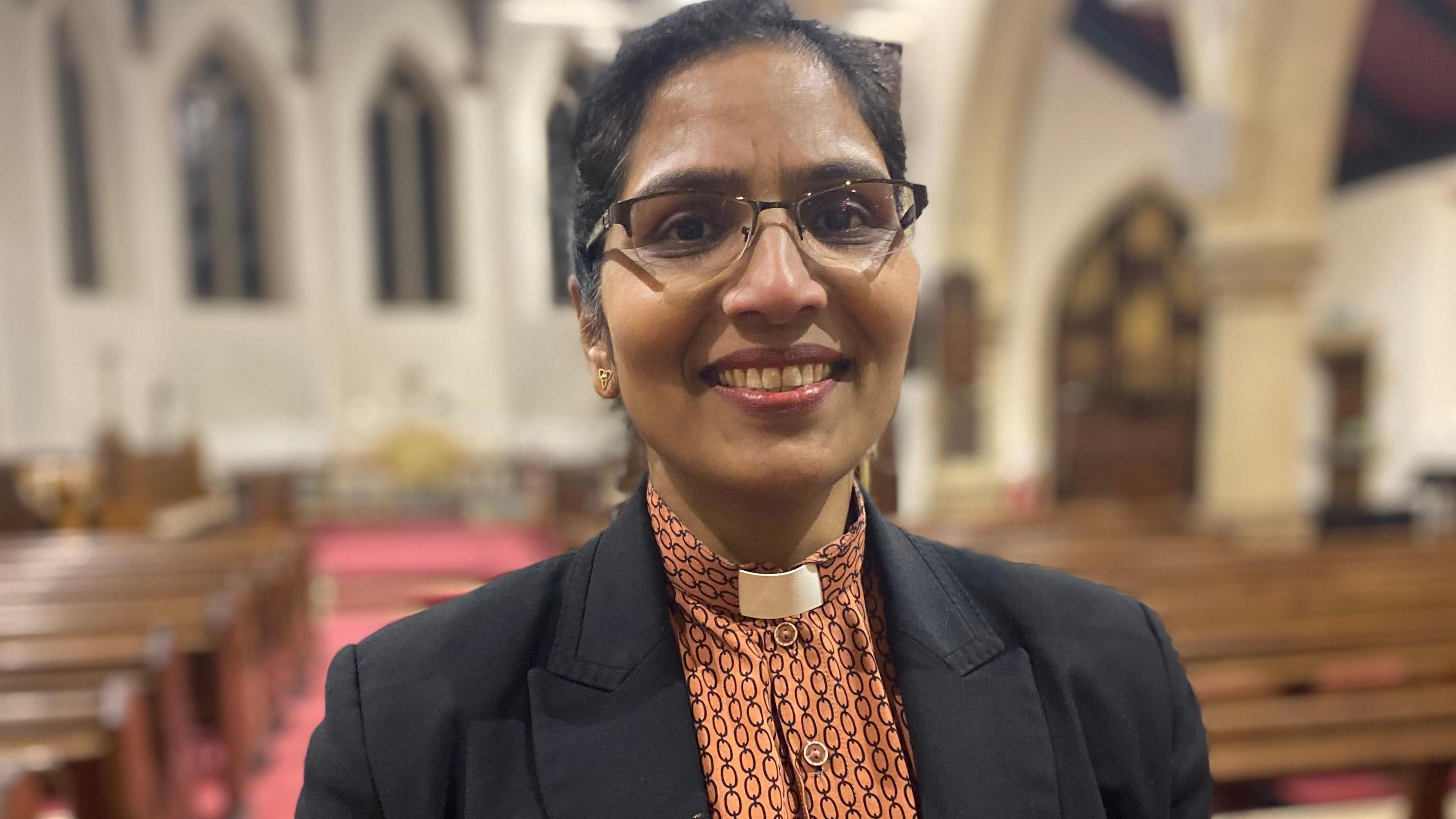 The vicar, Reverend Sarah Gill standing inside the church